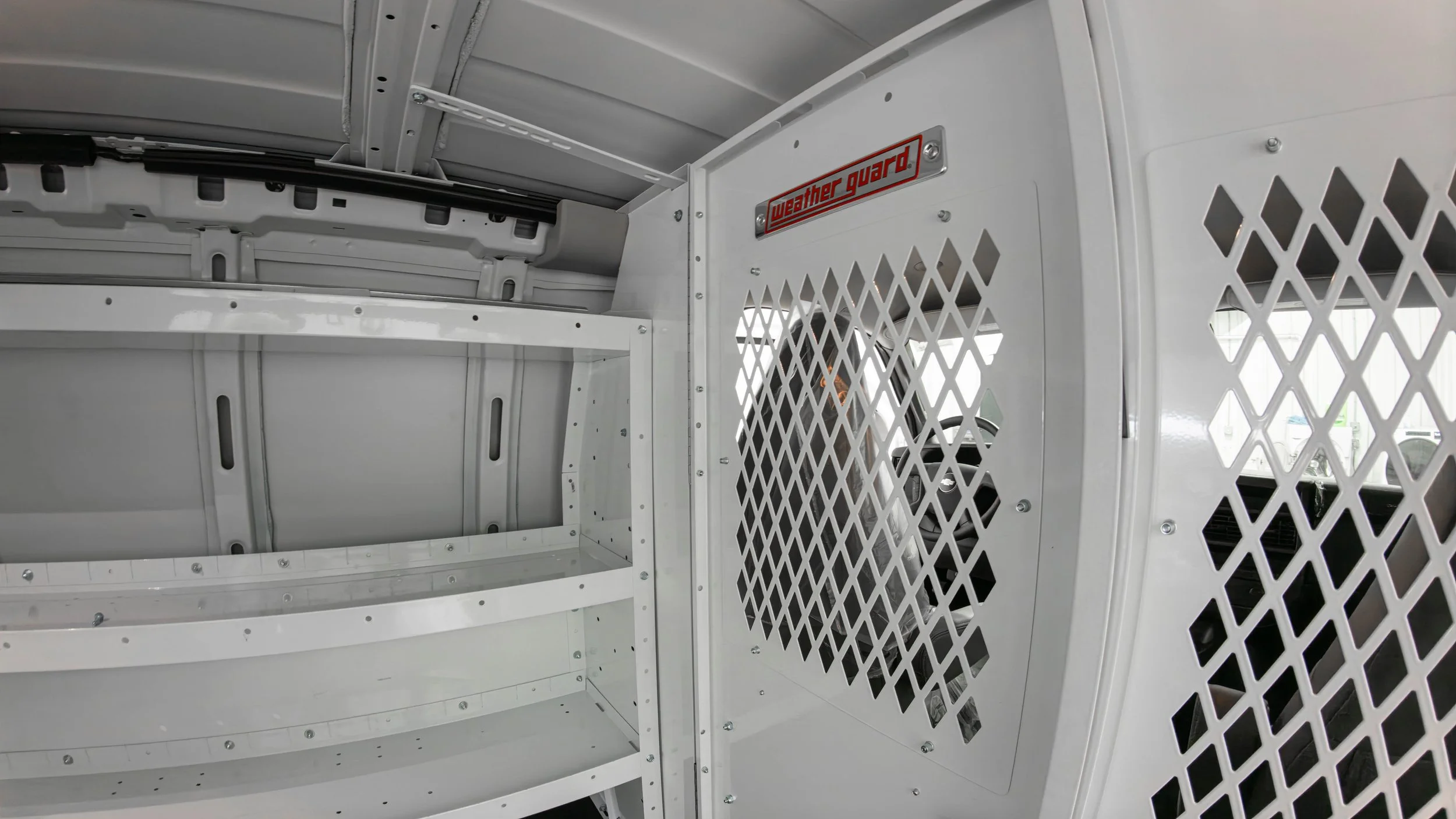 WeatherGuard shelving units and a screened bulkhead panel inside a Chevy Express work van