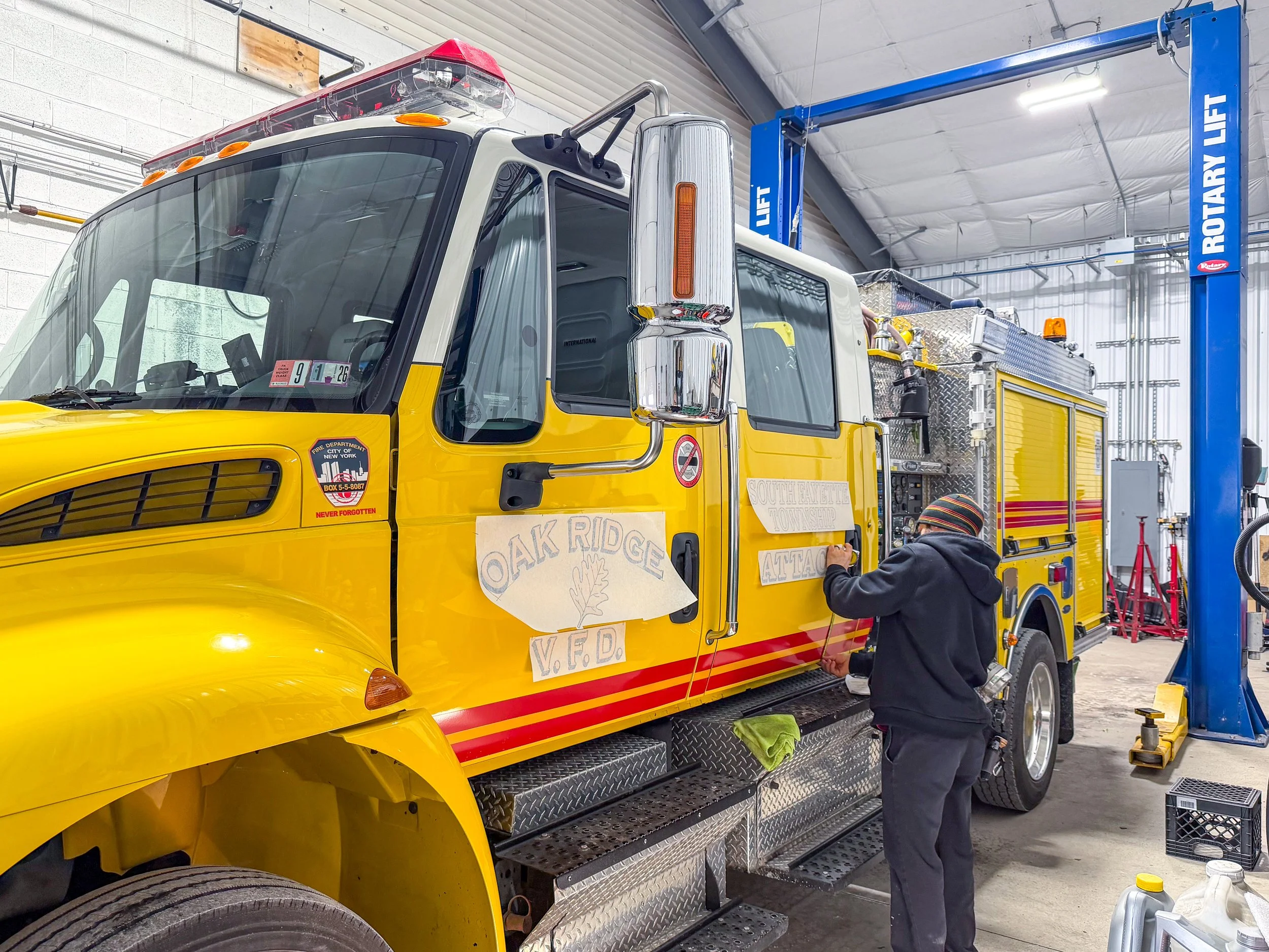 Custom vinyl vehicle graphics and lettering being installed on a fire truck in Bridgeville, PA at Xtreme Car & Truck Accessories.