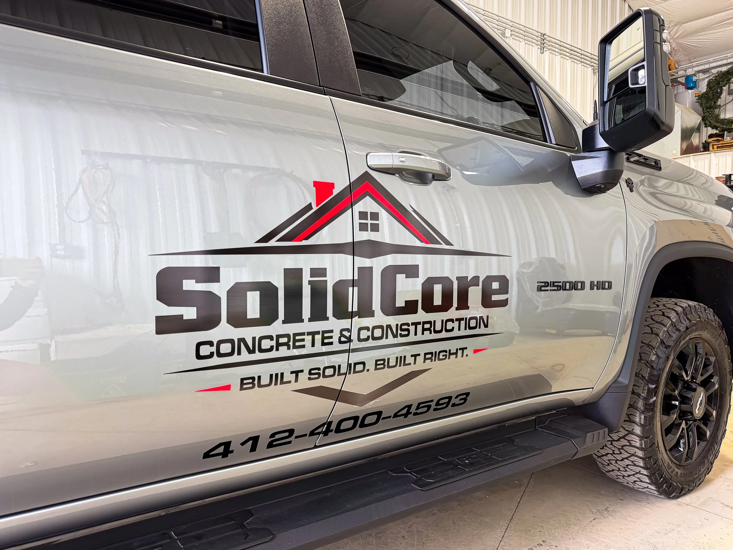 Custom vinyl graphics and business lettering installed on a Chevy Silverado 2500 HD work truck at Xtreme Car and Truck Accessories in Bridgeville PA