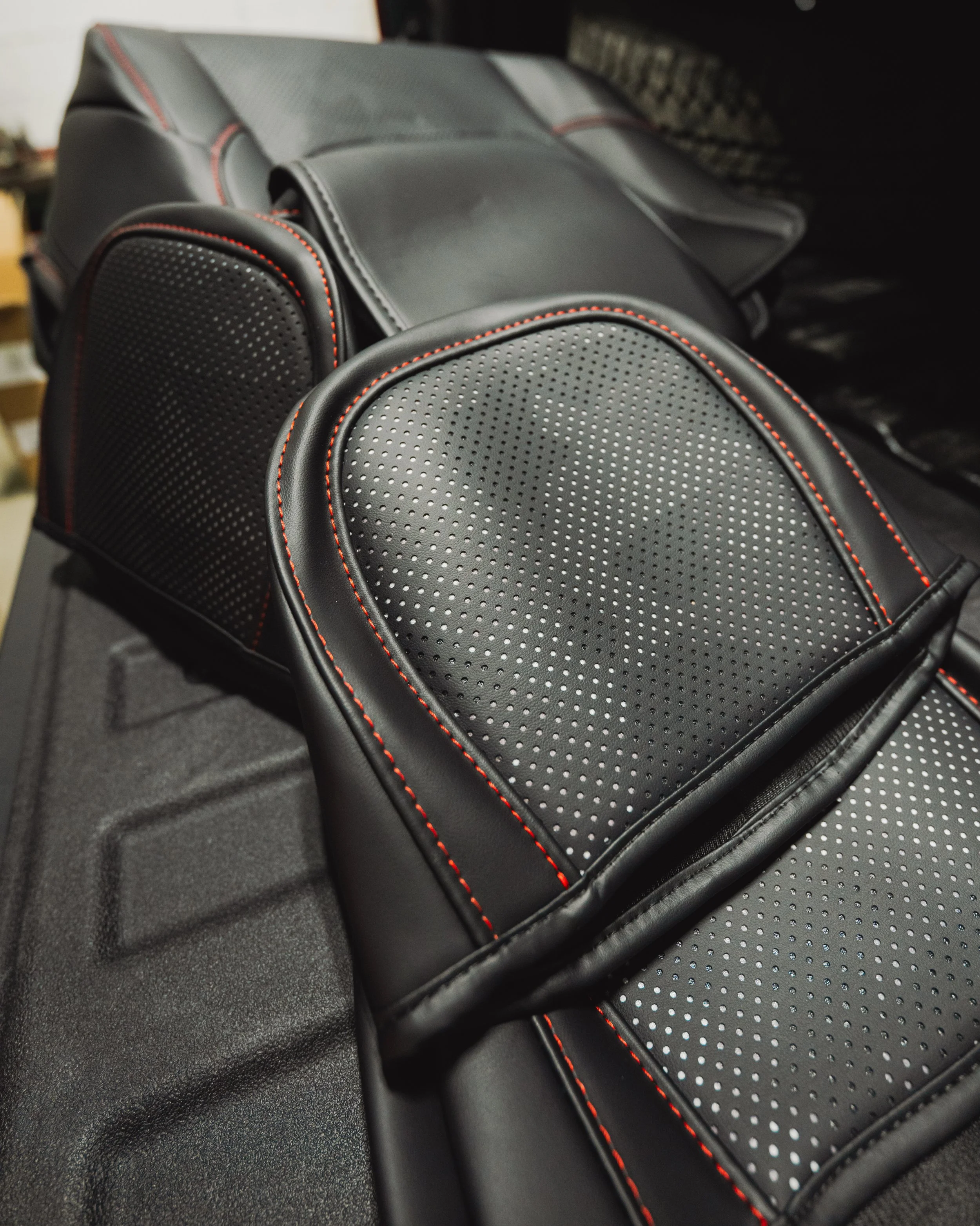 Customer-supplied custom black leather seat covers with red contrast stitching and perforated design installed at Xtreme Car & Truck Accessories in Bridgeville Pennsylvania