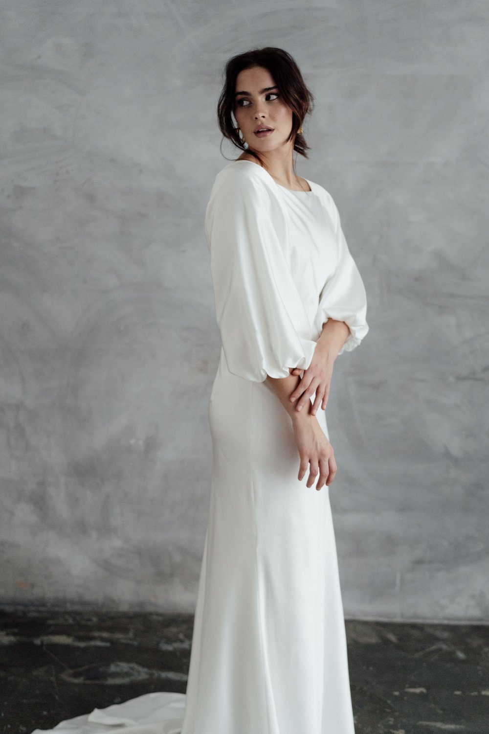 A radiant bride wearing natural ethical bridal makeup, glowing skin with a soft dewy finish, subtle champagne shimmer on the eyelids, softly defined brows, delicate rose-toned blush, and a muted petal-pink lip. Her complexion looks fresh breathable.
