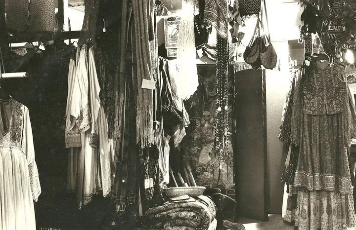 Clothing boutique with dresses and scarves on display, and miscellaneous garments hanging on the walls.