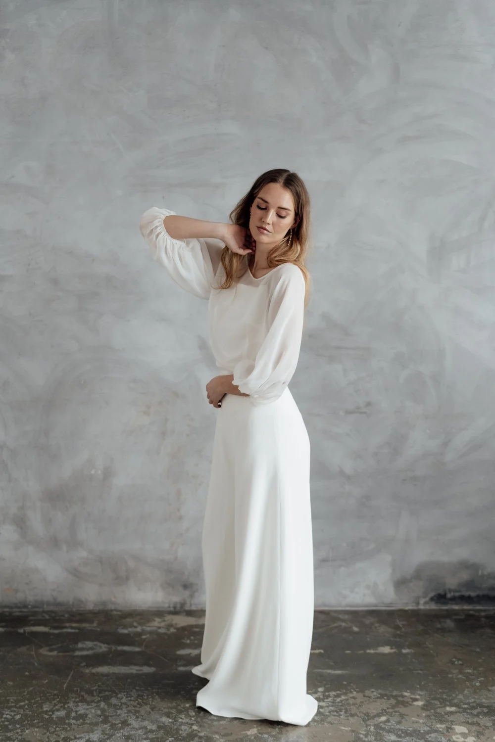 A radiant bride wearing natural ethical bridal makeup, glowing skin with a soft dewy finish, subtle champagne shimmer on the eyelids, softly defined brows, delicate rose-toned blush, and a muted petal-pink lip. Her complexion looks fresh breathable.
