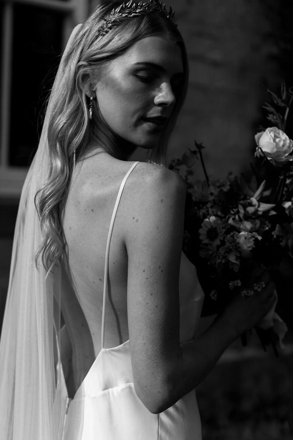 A radiant bride wearing natural ethical bridal makeup, glowing skin with a soft dewy finish, subtle champagne shimmer on the eyelids, softly defined brows, delicate rose-toned blush, and a muted petal-pink lip. Her complexion looks fresh breathable.
