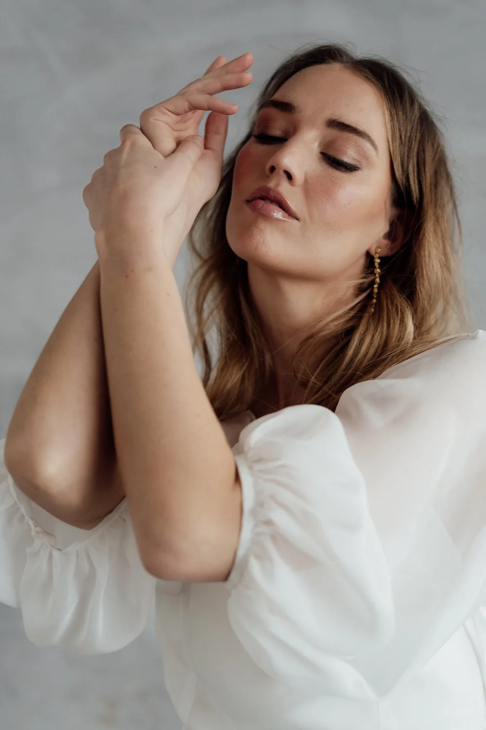 A radiant bride wearing natural ethical bridal makeup, glowing skin with a soft dewy finish, subtle champagne shimmer on the eyelids, softly defined brows, delicate rose-toned blush, and a muted petal-pink lip. Her complexion looks fresh  breathable.