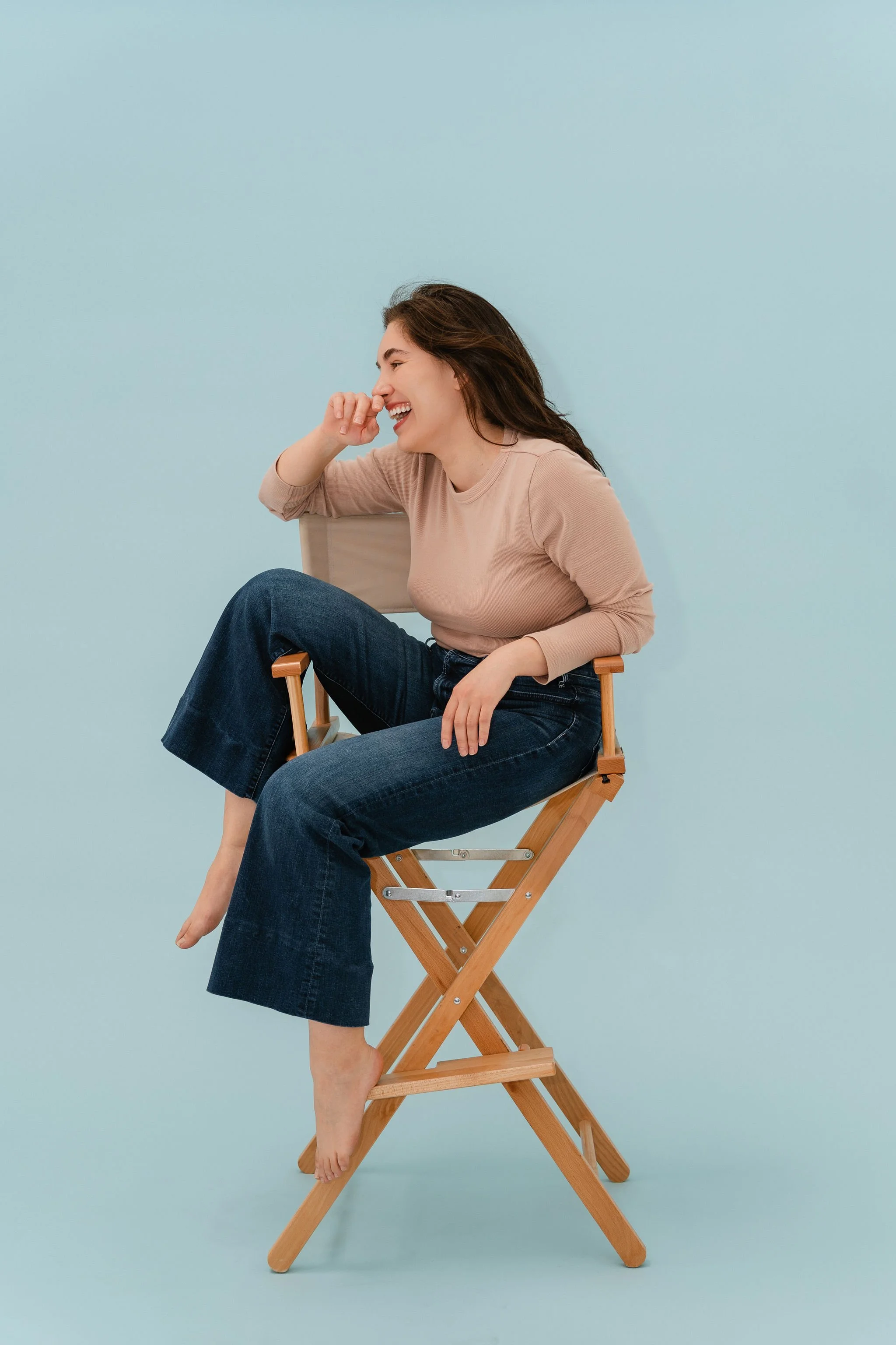 Monauar laughs while sitting in a director's chair