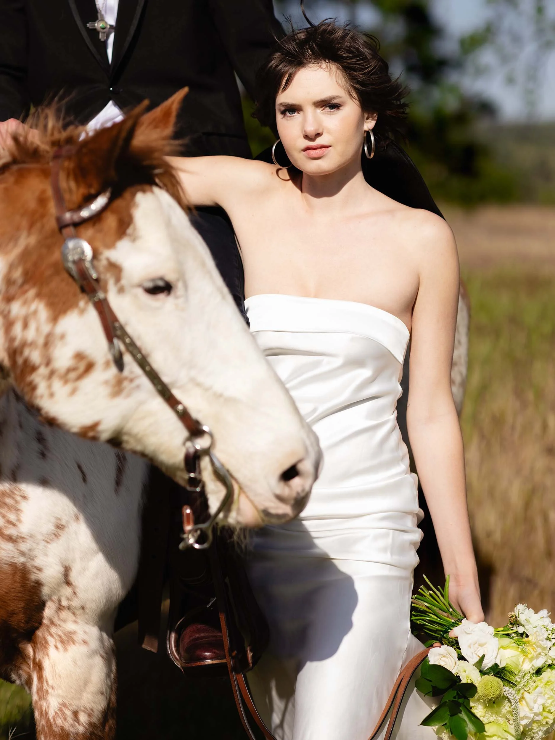 Western editorial bride poses next to her husband on horseback during a Columbia River Gorge elopement.