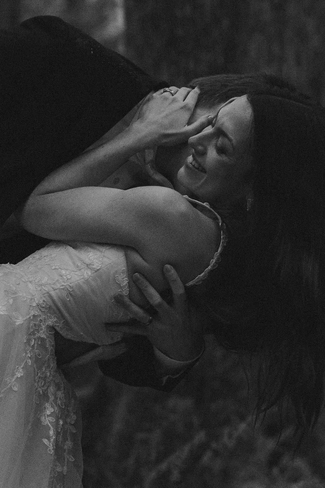 Black and white edit showing a wedding couple embracing and laughing during their elopement in Olympic National Park.
