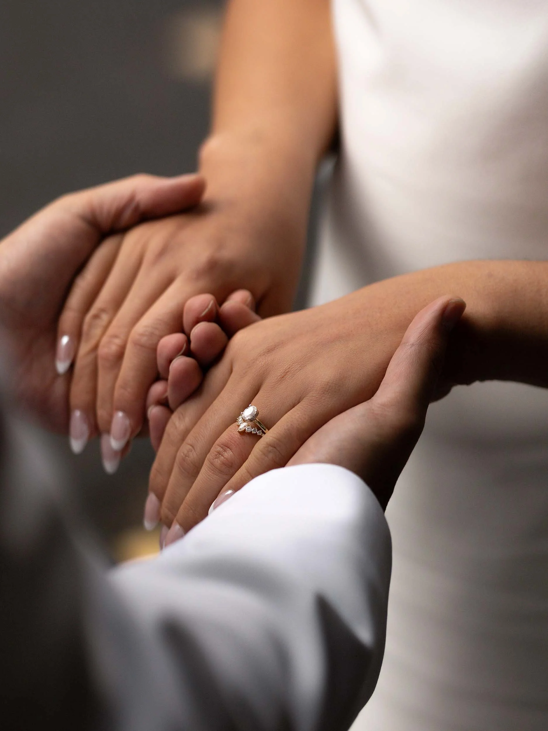 Groom holds bride's hands, showing off her wedding rings during a micro wedding near Mount Rainier.