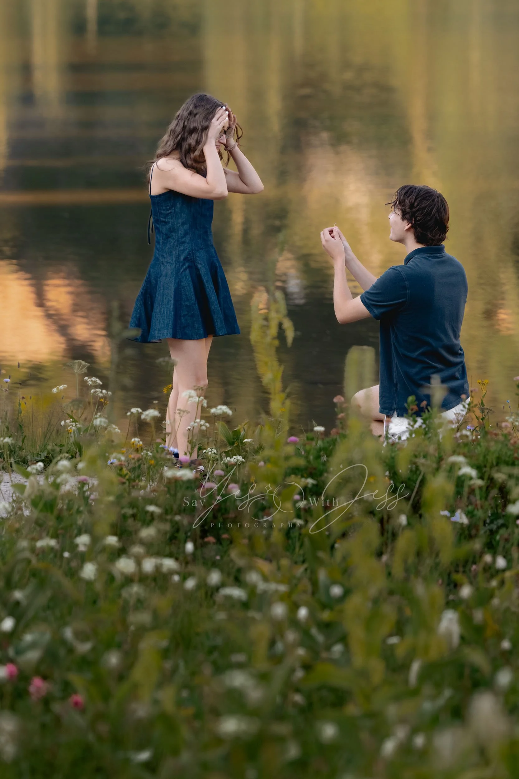 A young man proposes marriage on one knee at Tipsoo lake, surrounded by wildflowers.