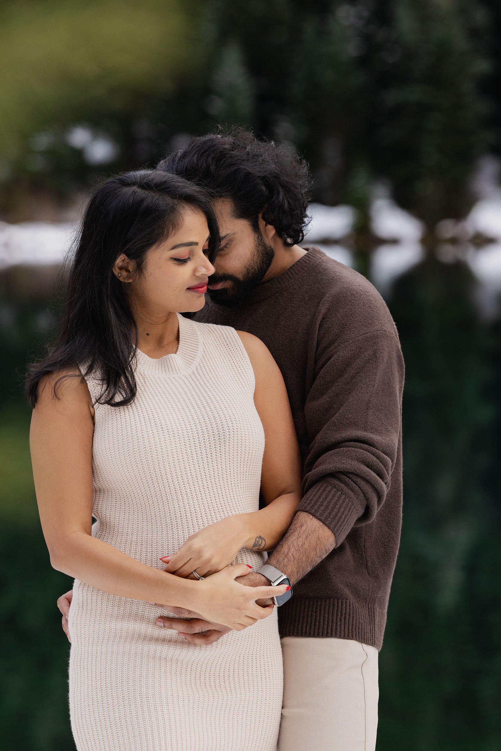 An expecting couple embrace at Gold Creek Pond during their winter maternity and gender reveal session.

