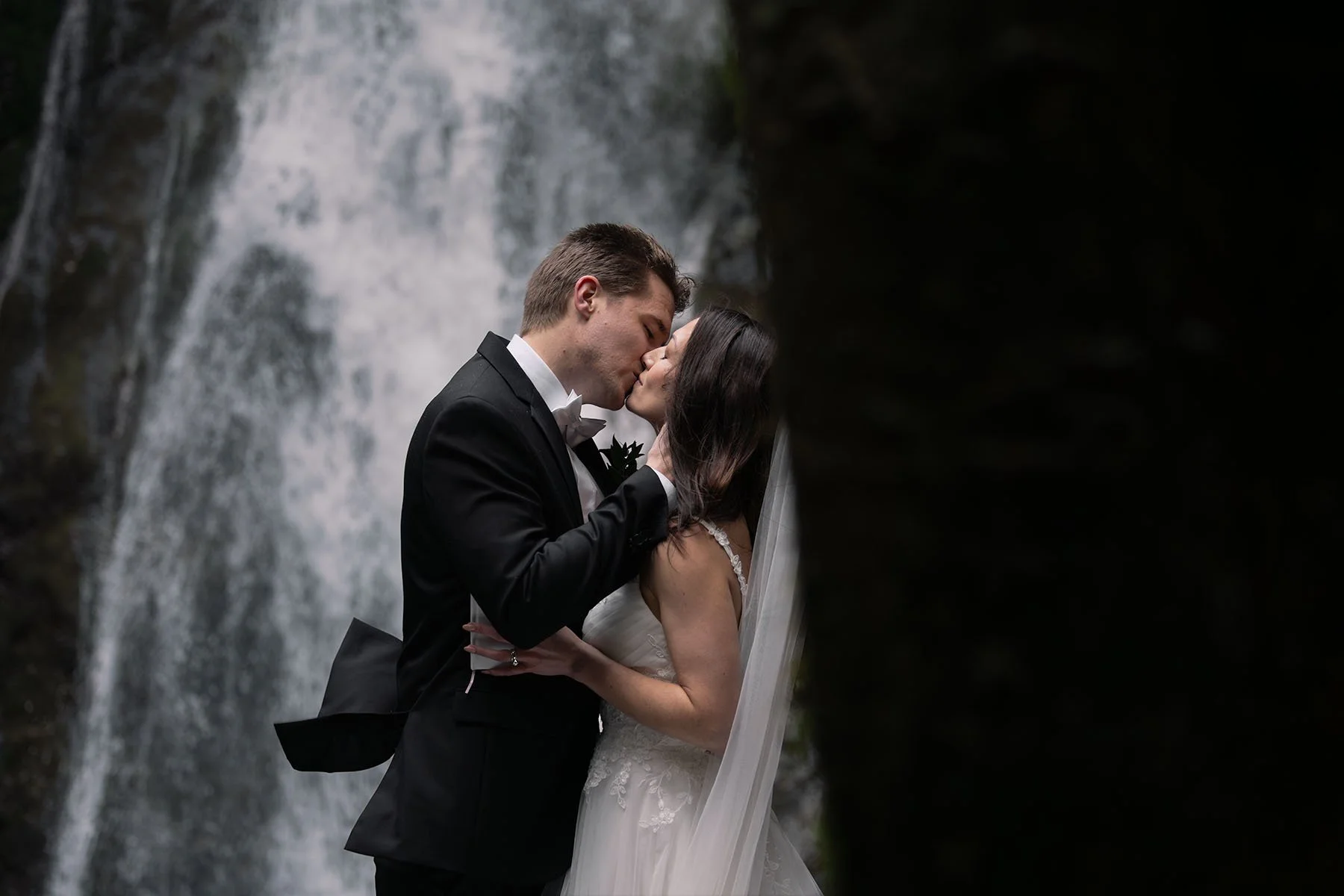 A couple shares a first kiss in front of Madison Falls at their Olympic National Park elopement ceremony.