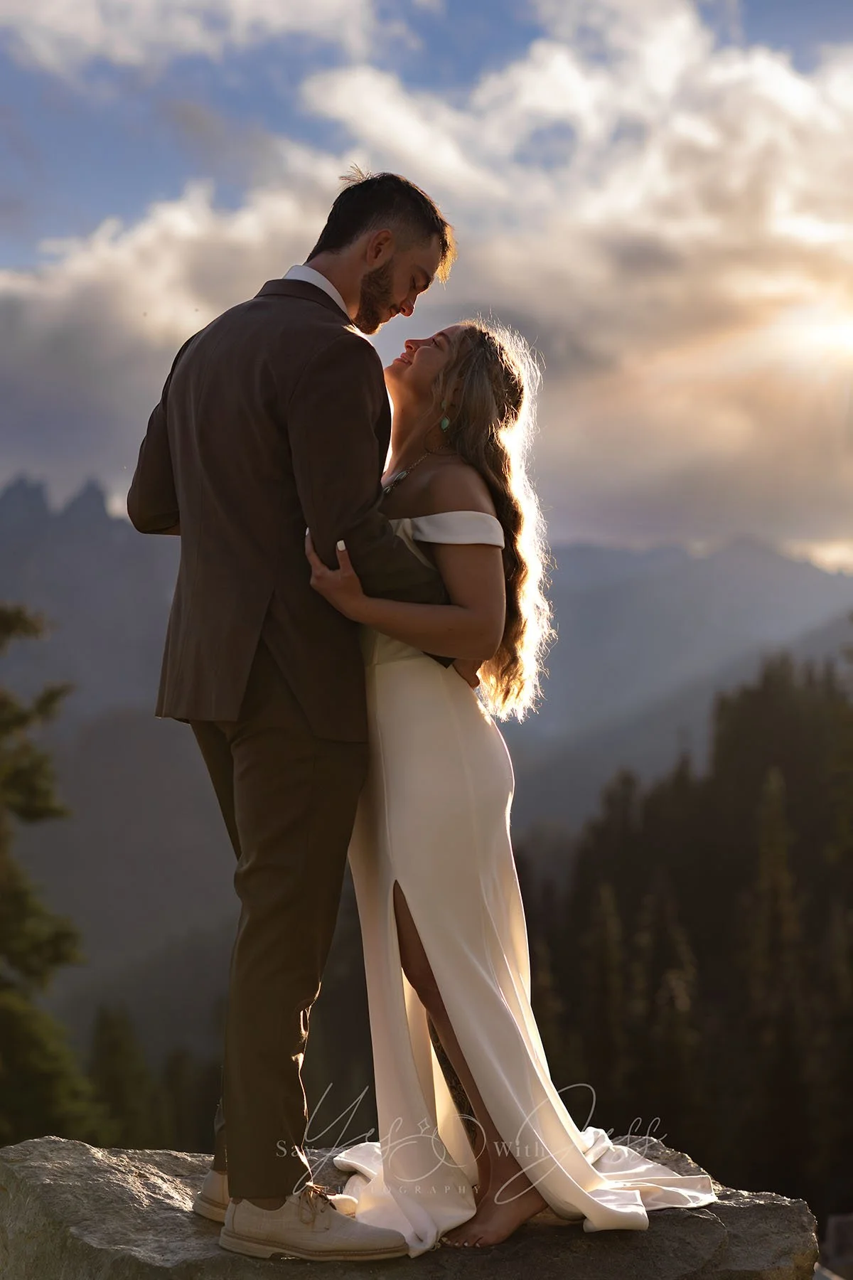 A bride and groom are backlit by the sun and mountains as they smile at each other on their elopement day at Mount Rainier.