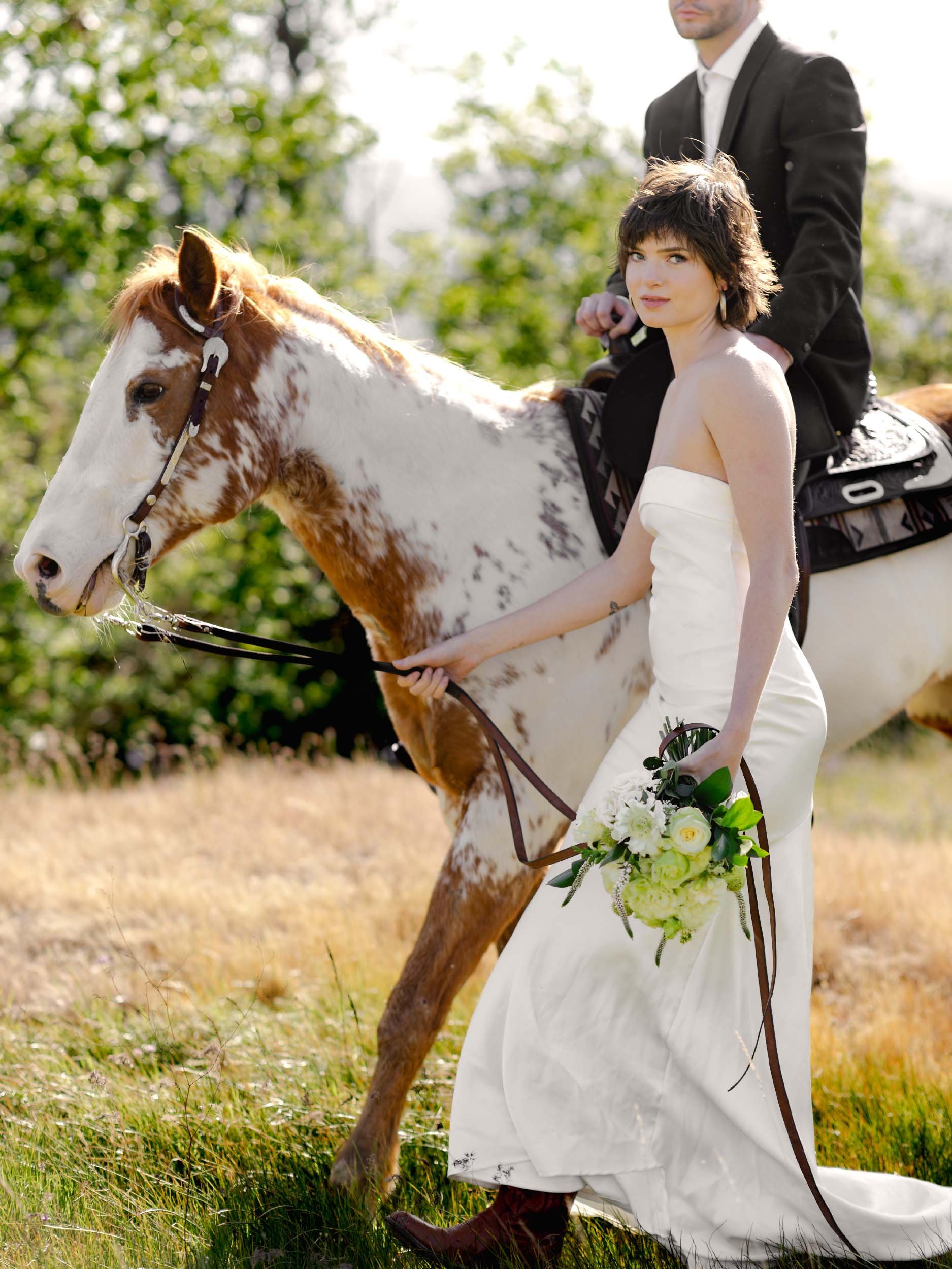 Editorial bride walks a western horse carrying her husband through a meadow near the Columbia River Gorge at their elopement.