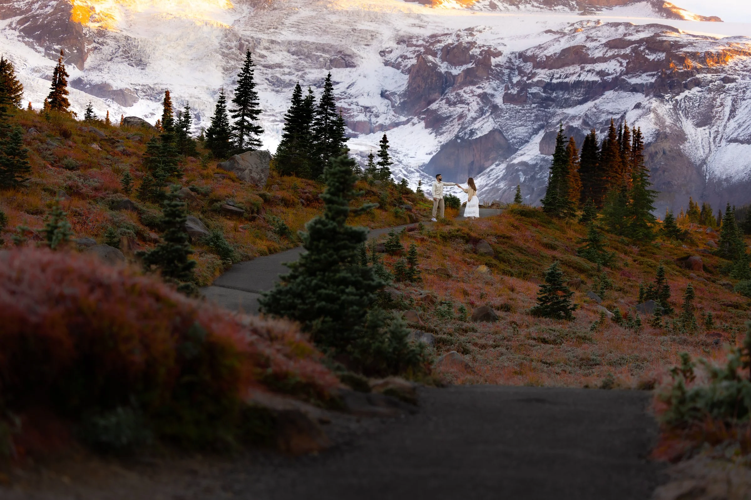 A couple dance in front of Mount Rainier, surrounded by vibrant fall foliage during an engagement session.