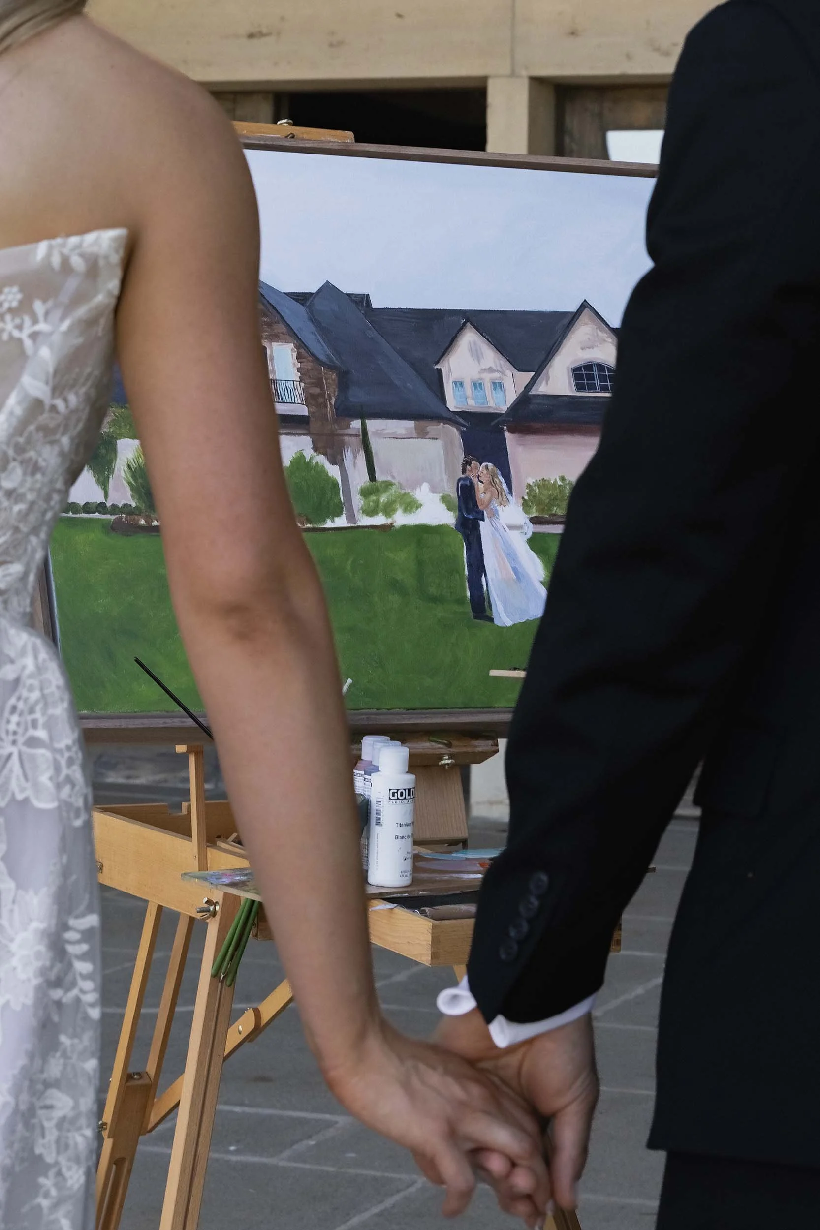 A bride and groom hold hands as they view the live painting by Artsy Adventurist on their wedding day in Oregon.