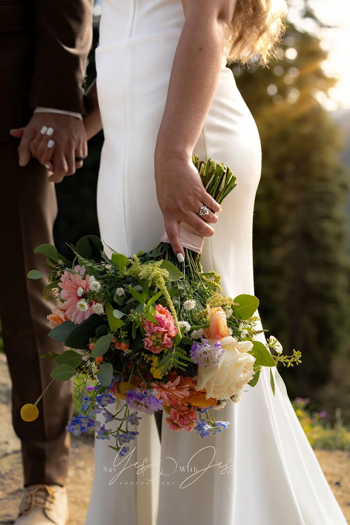 Crop of a bride holding her husband's hand and her bouquet down by her side, showing off her wedding rings on their wedding day at Mount Rainier.
