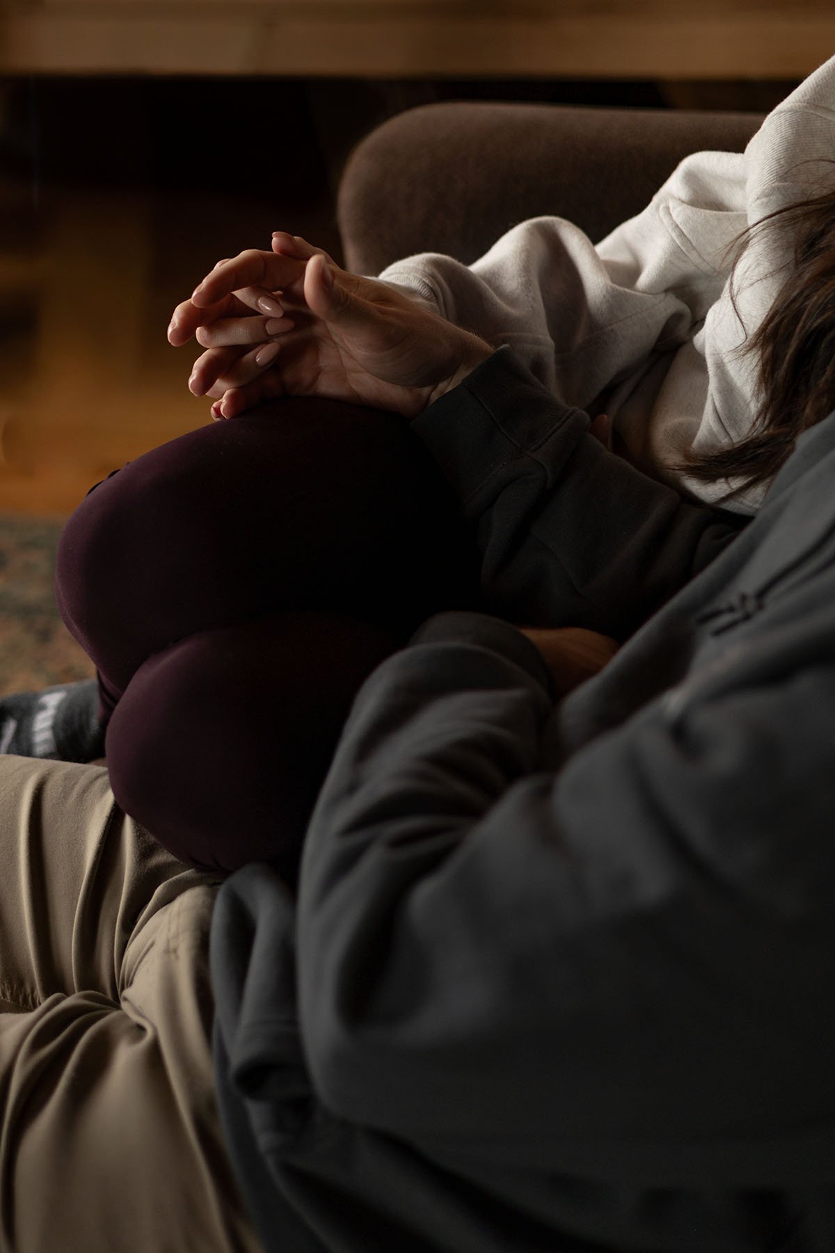 A couple hold hands curled up on a couch before they get dressed for their elopement day
