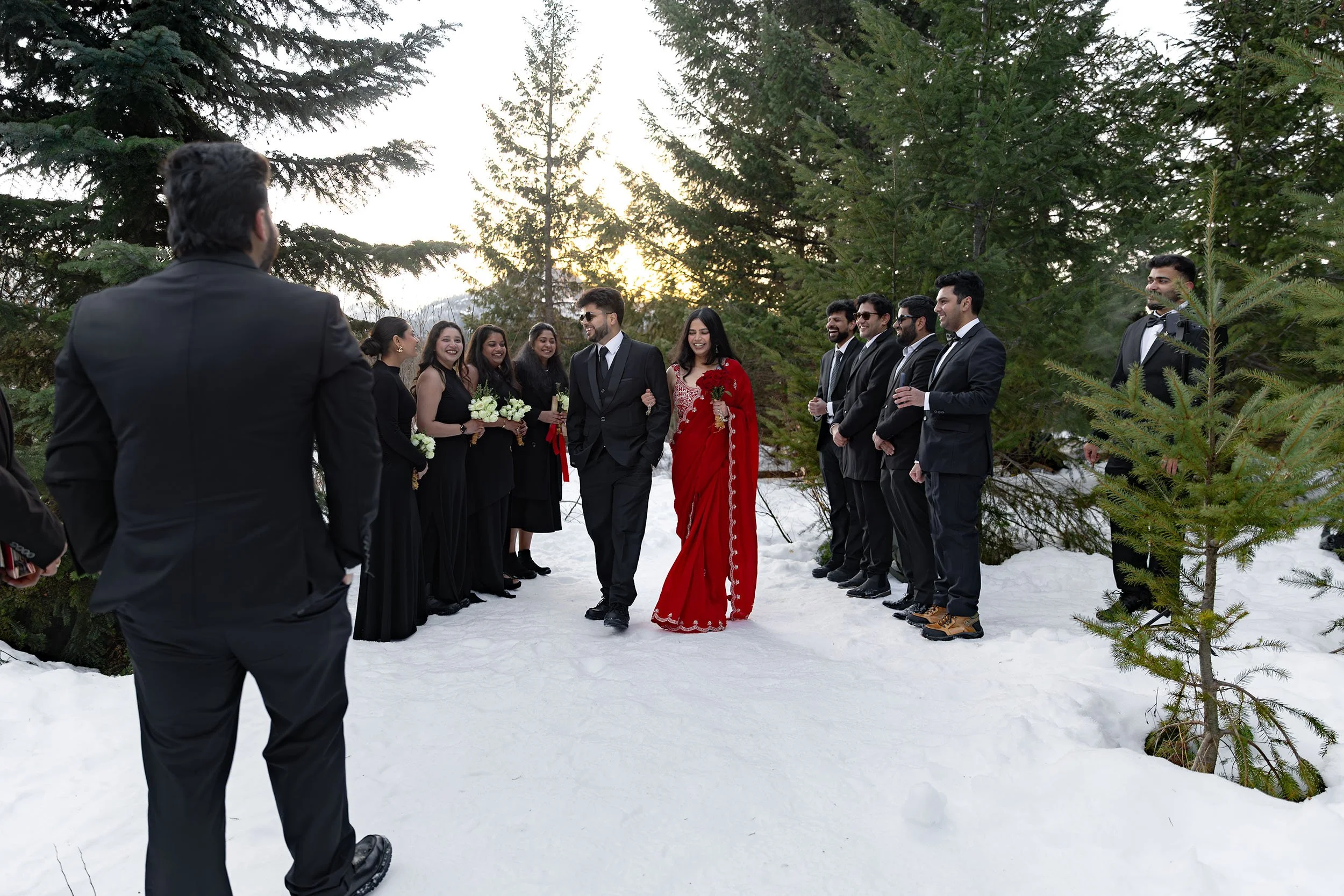 An Indian bride walks a metaphorical aisle with her brother in the snow at Gold Creek Pond during their intimate winter wedding.