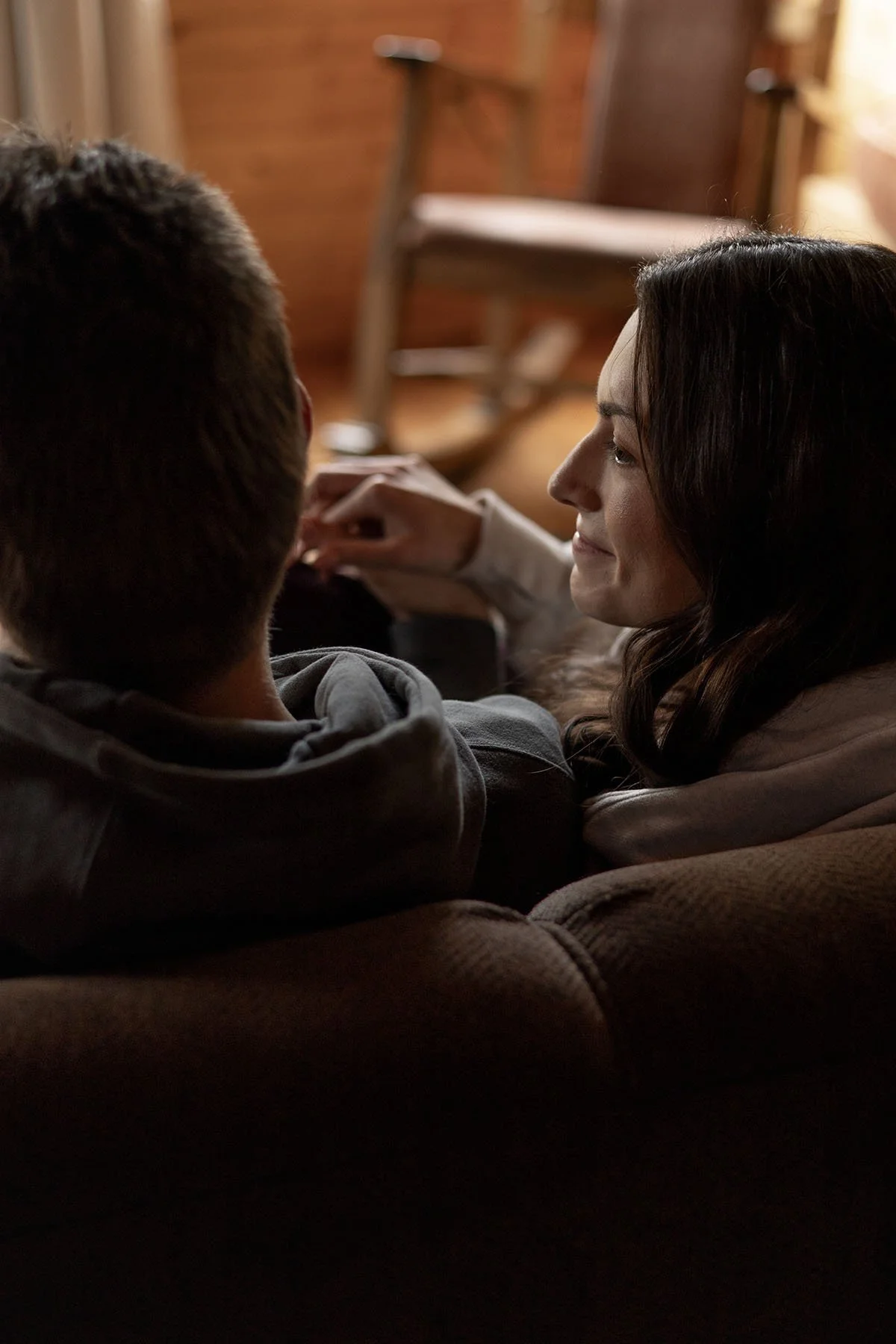 A couple hold hands curled up on a couch before they get dressed for their elopement day