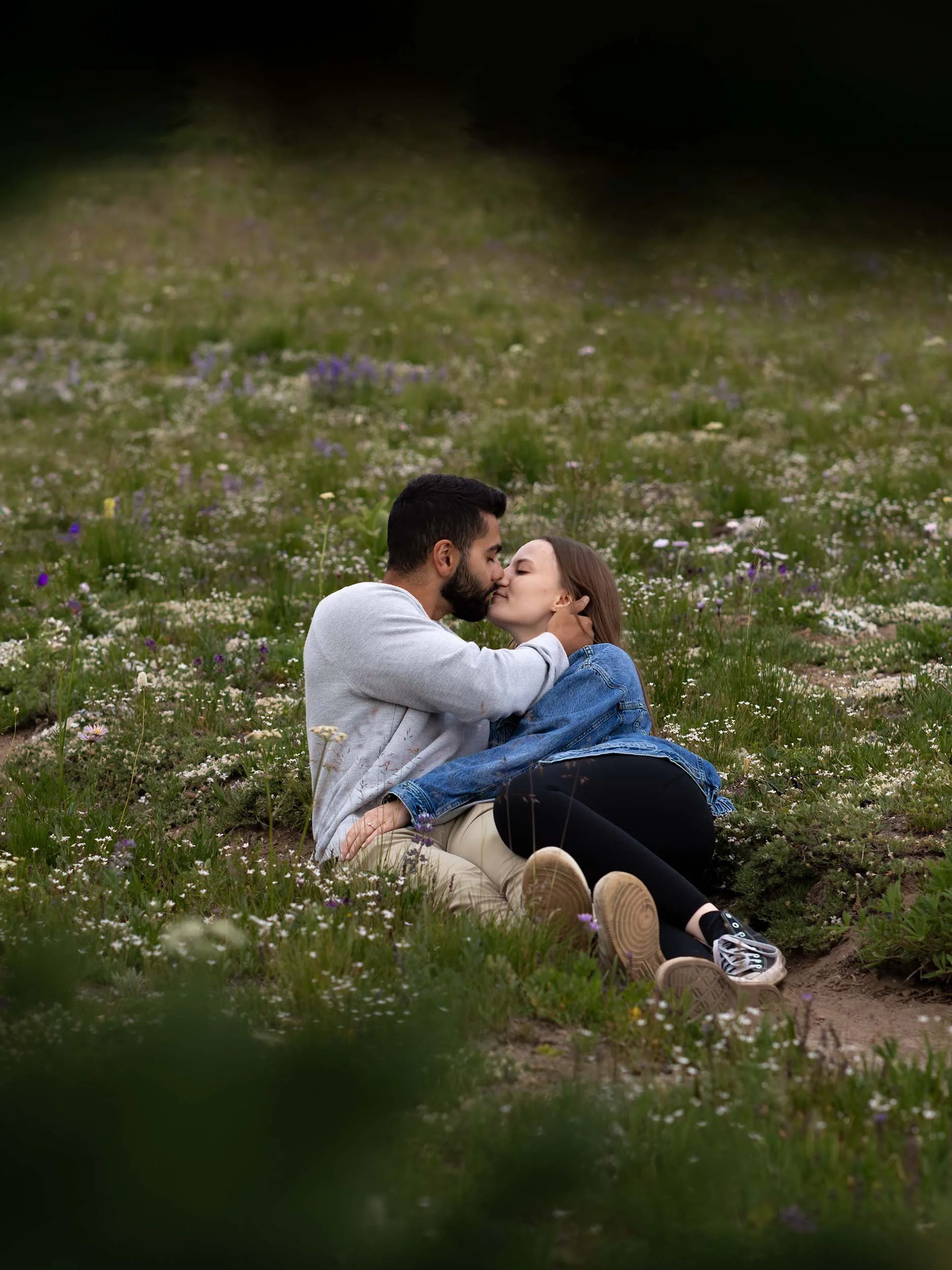 A newly engaged couple lay in a field of wildflowers at Mount Rainier after his marriage proposal. 
