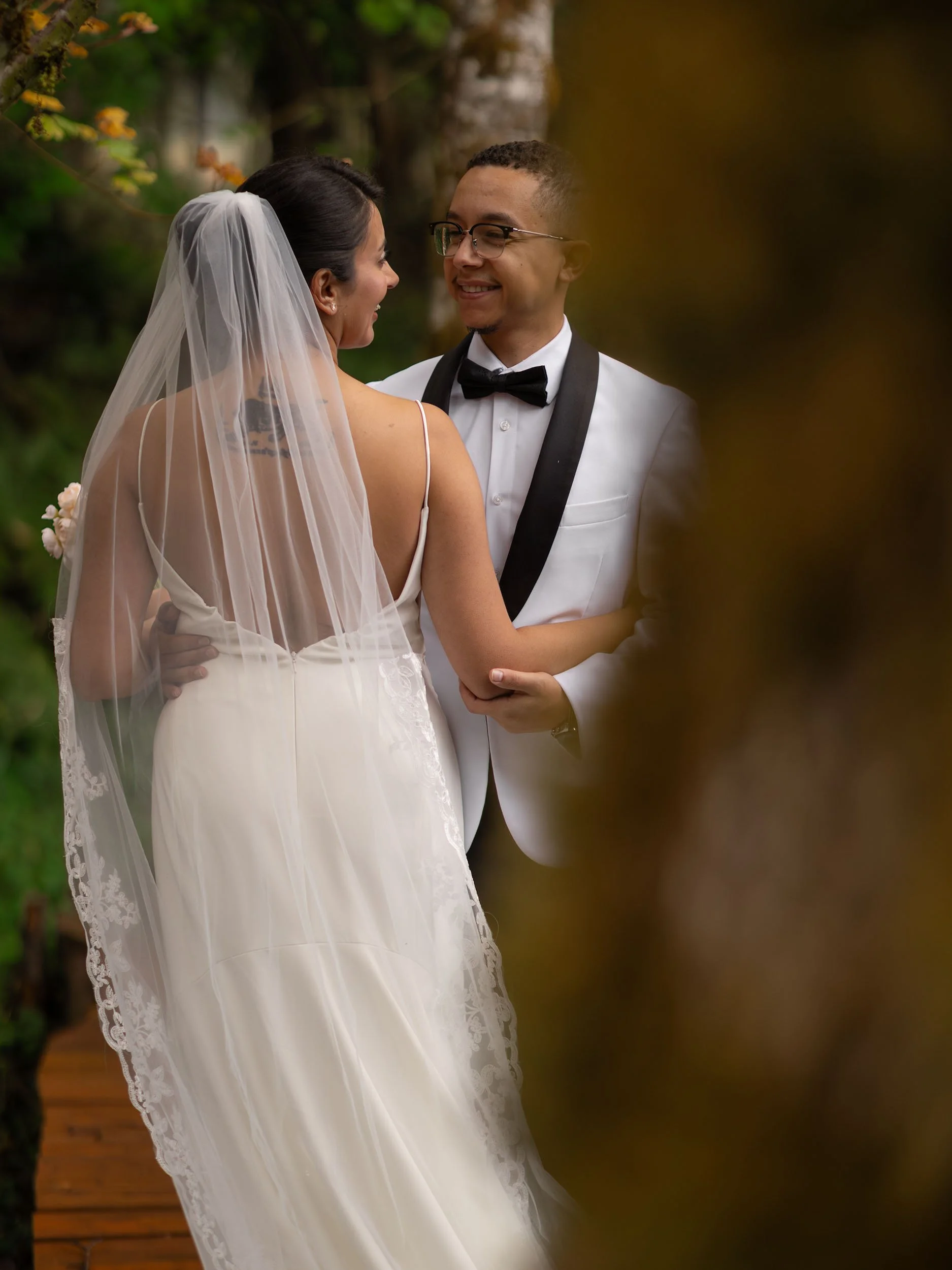 Laughing bride and groom embrace behind a tree after their intimate wedding ceremony near Mount Rainier.