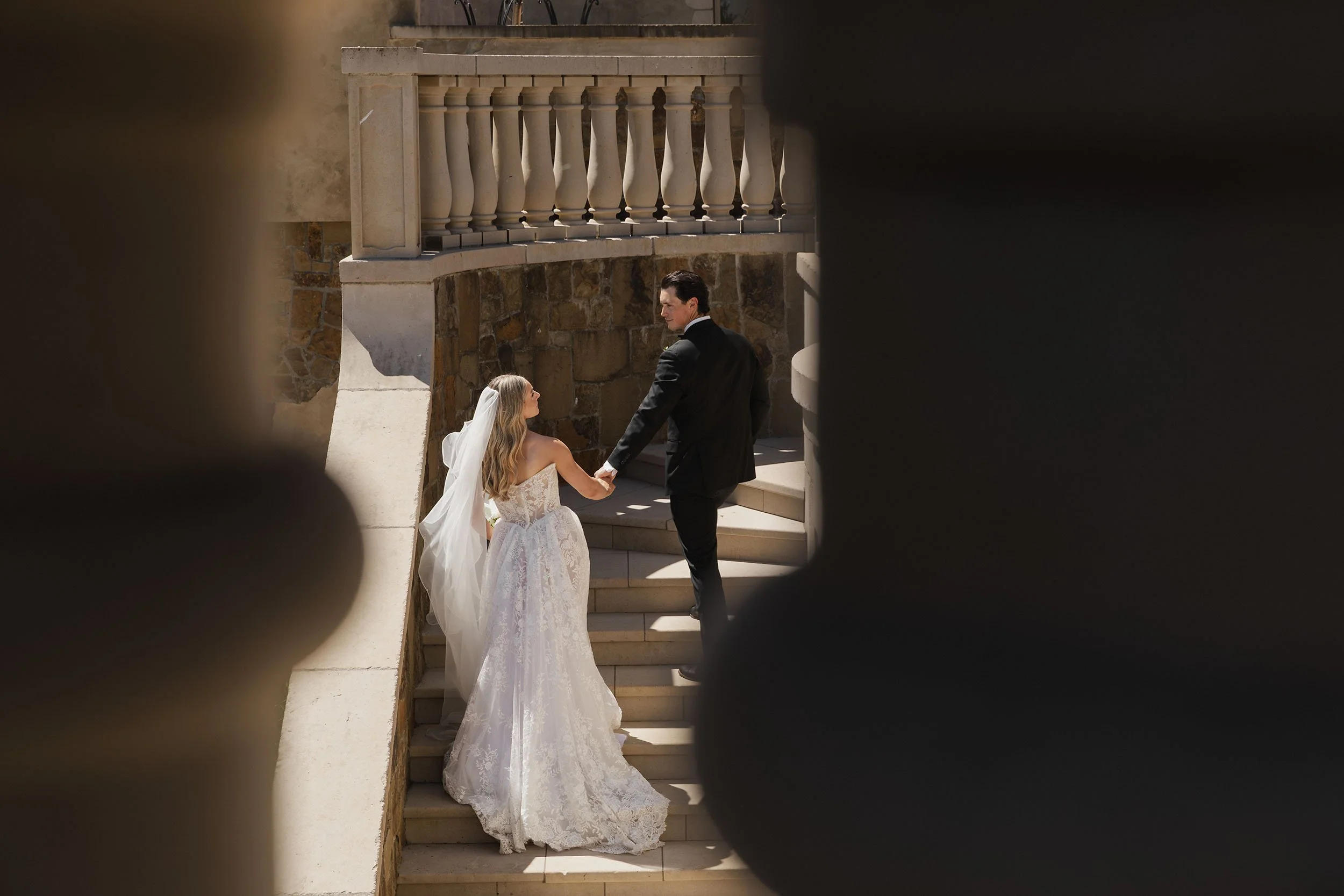 Wedding couple walk up the stone grand-staircase at luxury event venue Chateau De Lis in Oregon.