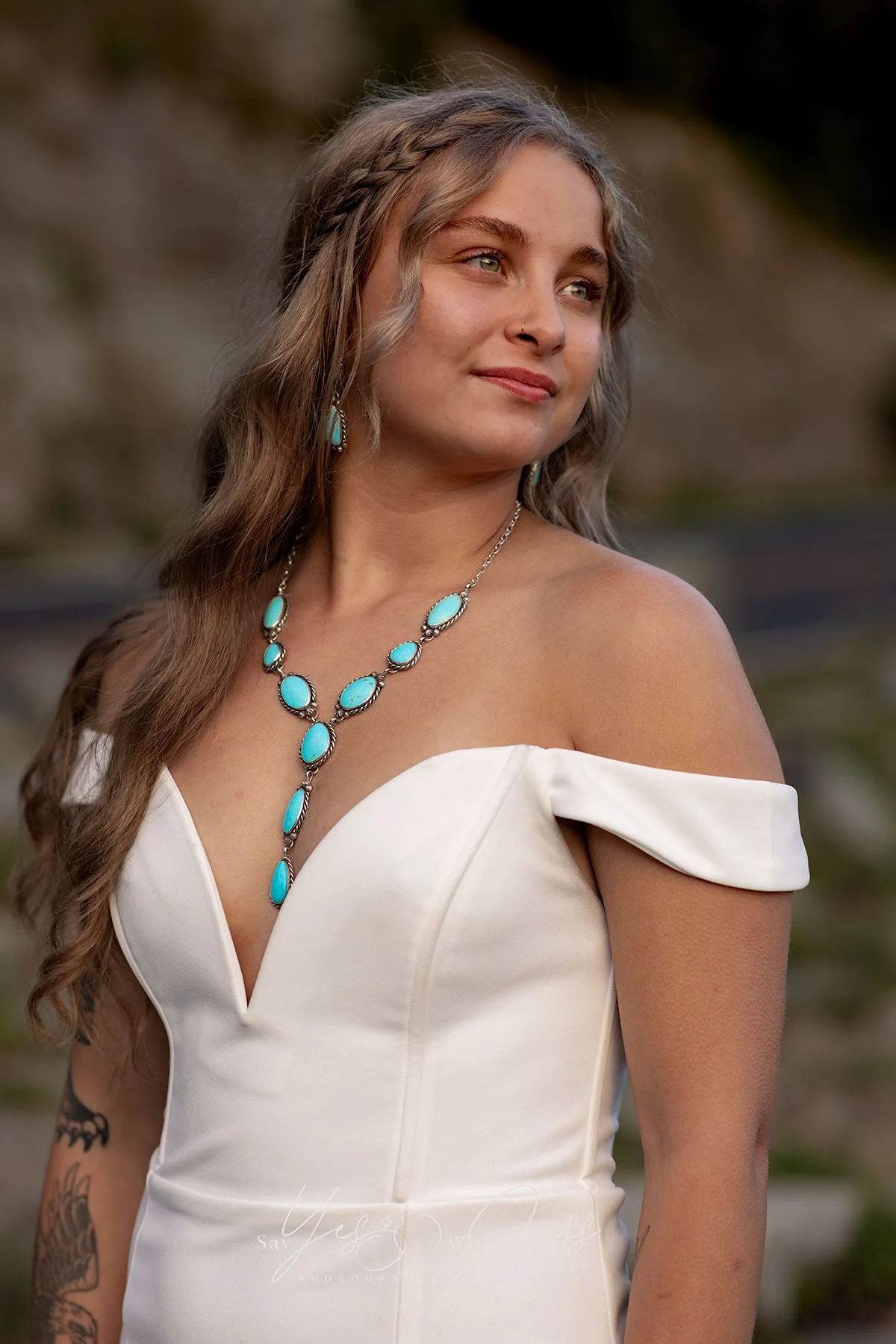 A bride looks toward the sunset smiling softly at her Mount Rainier elopement. She wears handmade turquoise jewelry.
