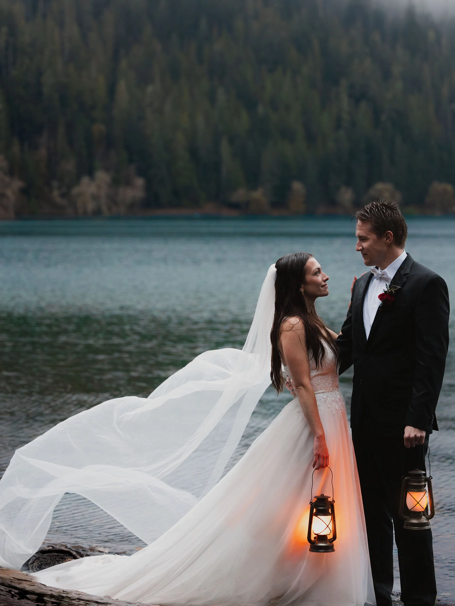 Wedding couple at Lake Crescent in the rain holding lanterns during an Olympic National Park elopement.