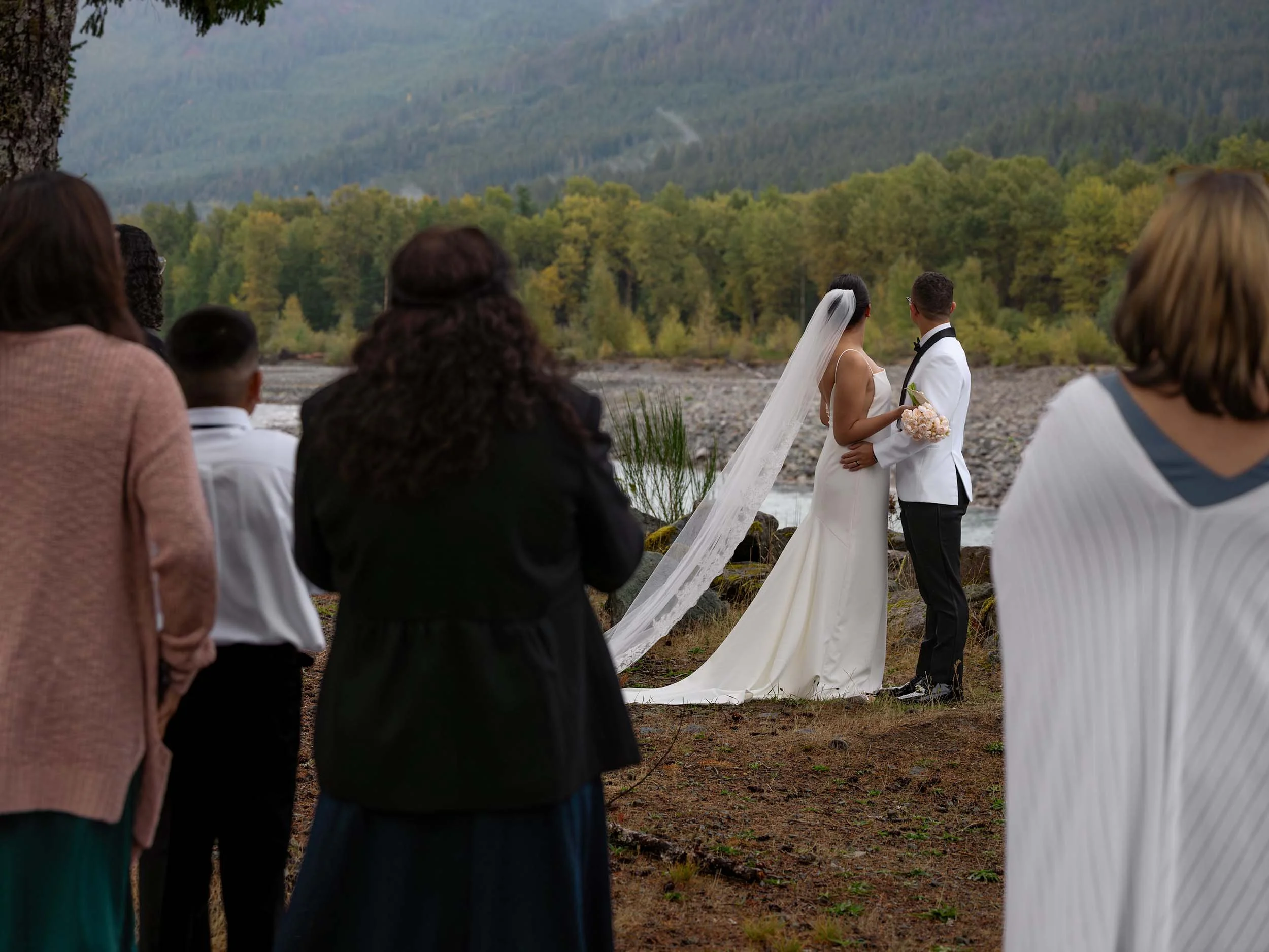 Micro wedding couple look out at the landscape over the Nisqually River during their ceremony near Mount Rainier National Park