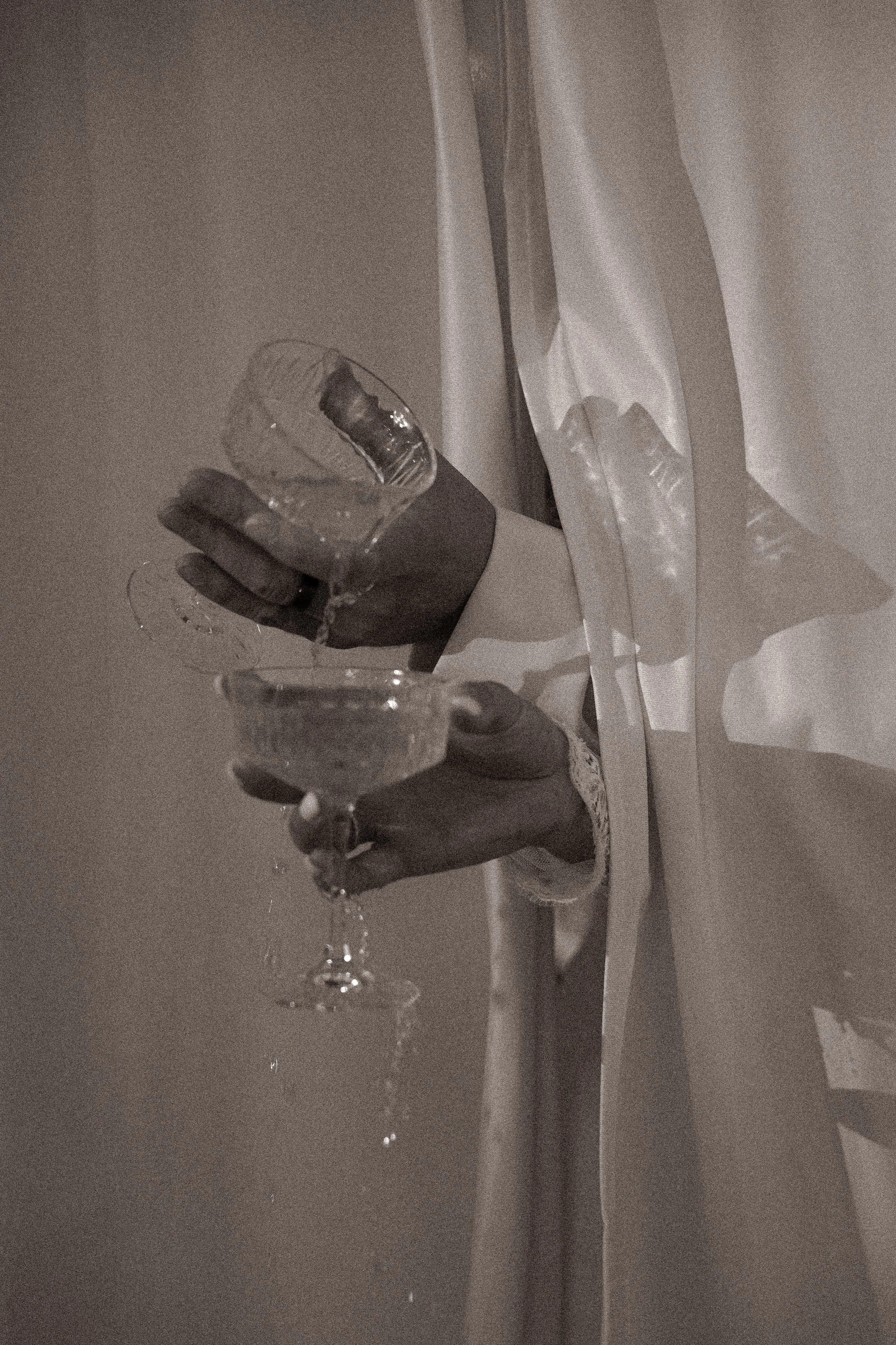A person in a white shirt holding a glass of water and a plate, pouring water into the glass.