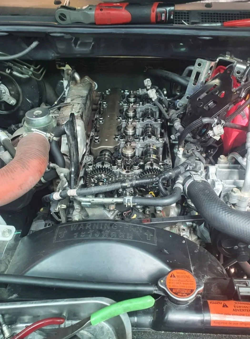 Close-up of a car engine with a disassembled cylinder head and various engine components visible.