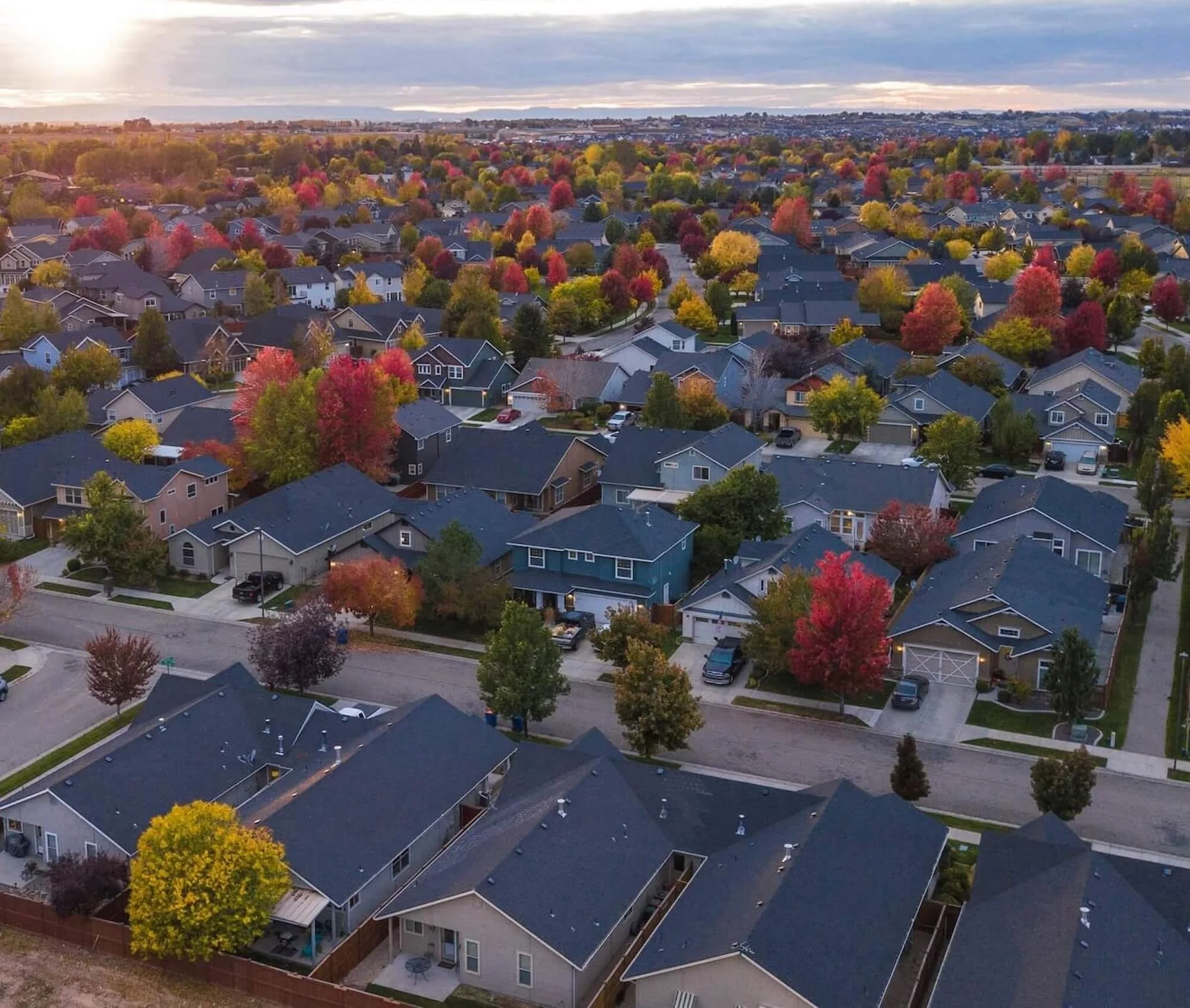Aerial view of a suburban neighborhood with houses and colorful autumn trees.
