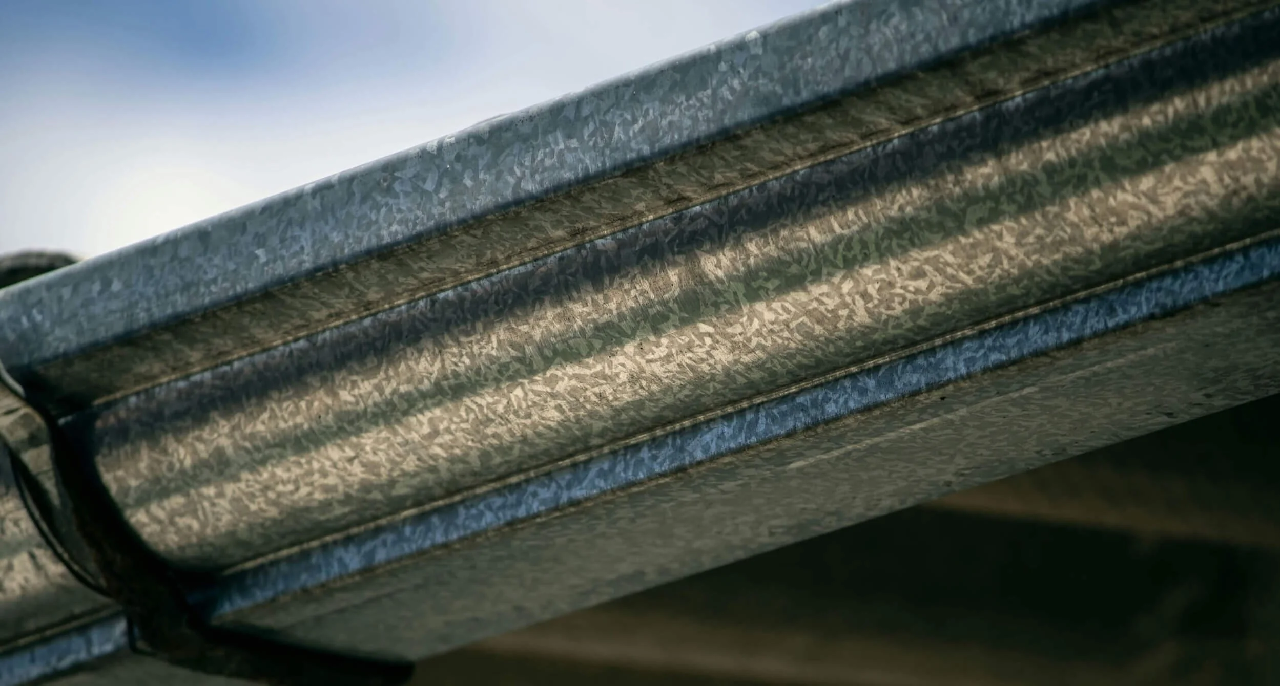 Close-up of the underside of a metallic or steel bench or table, showing its textured surface and construction details.