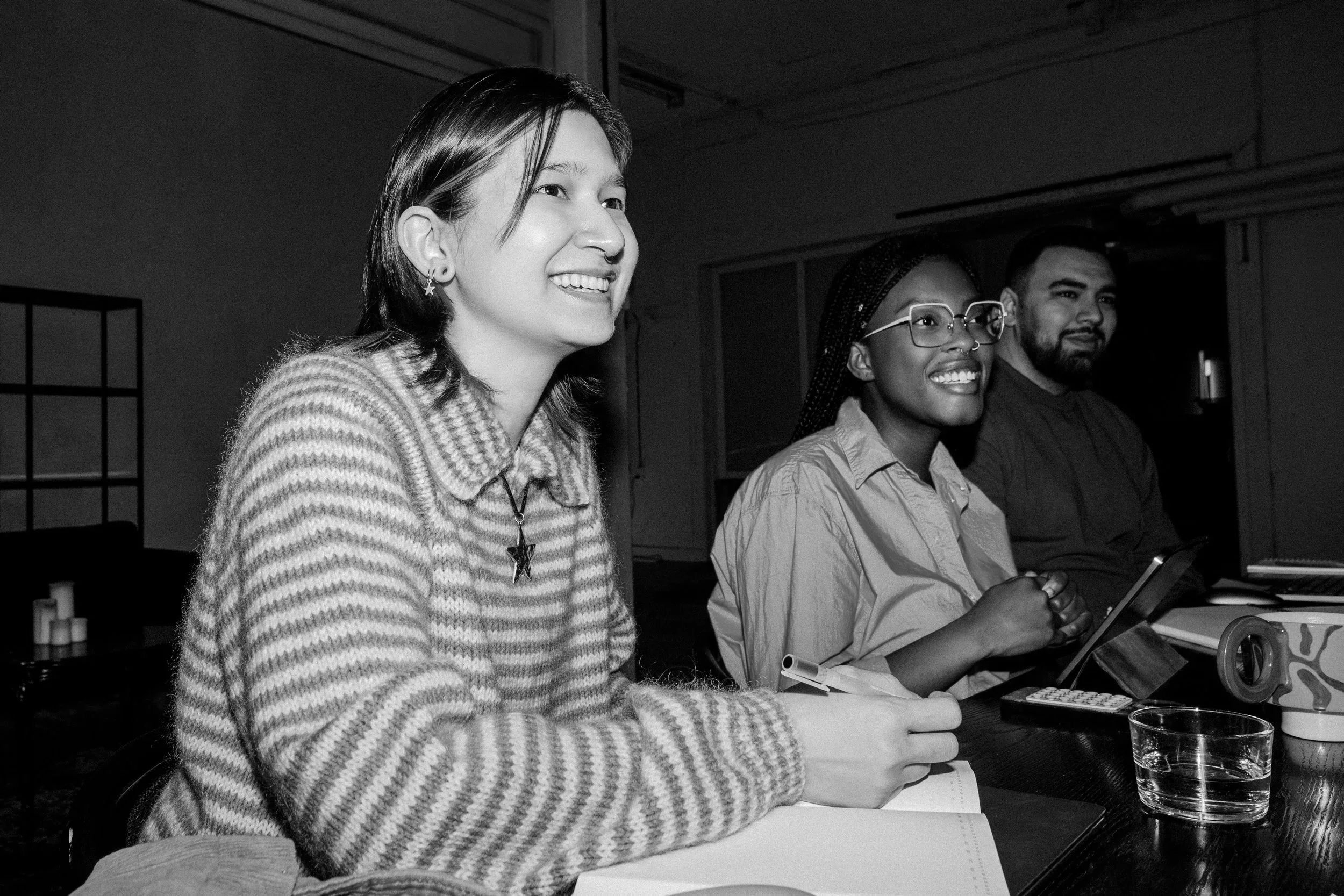 Trois personnes assises à une table, souriantes, dans un environnement intérieur.