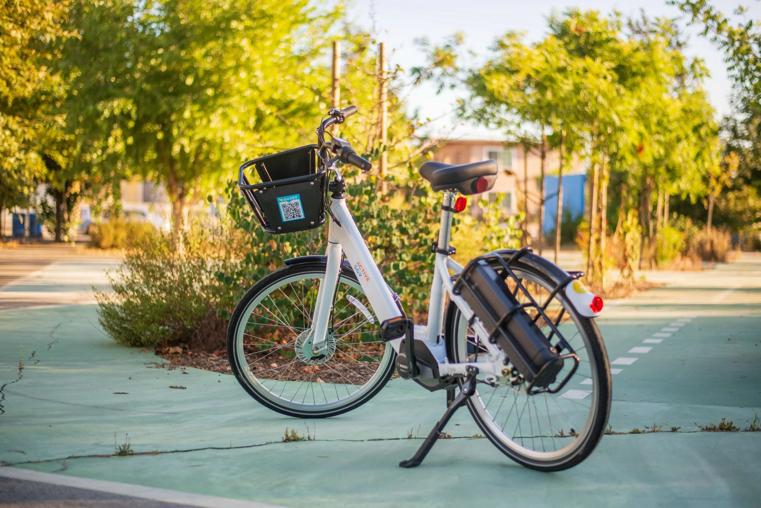 An electric bicycle parked on a bike lane surrounded by trees and greenery during daytime.