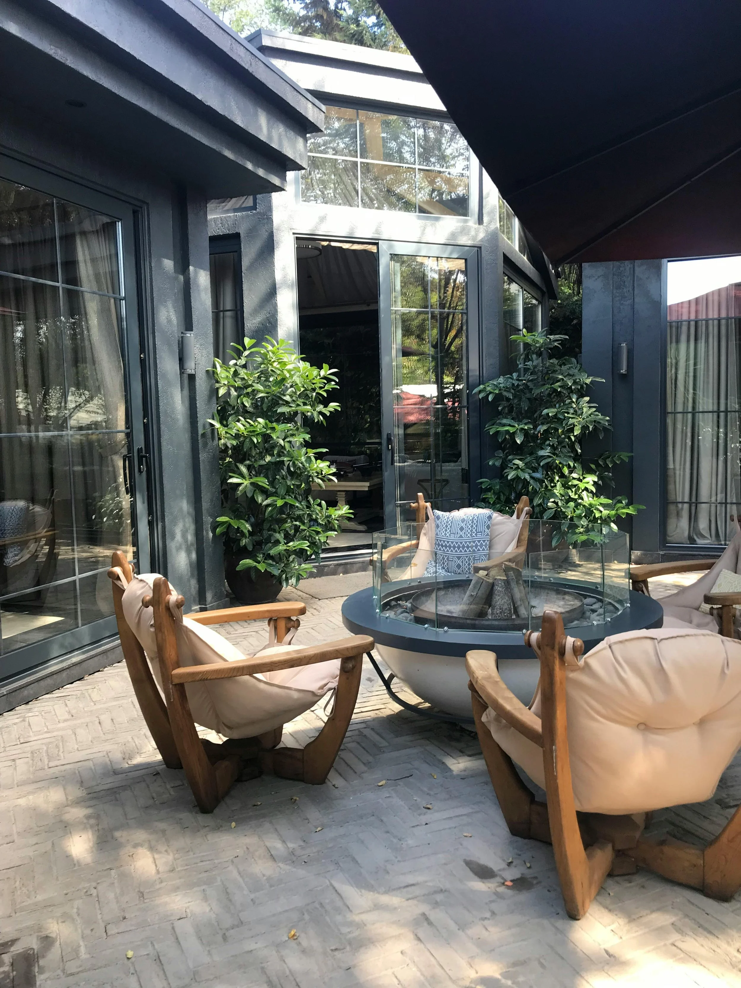 Image of a patio arrangement with a table and chairs with potted plants in front of a black patio door