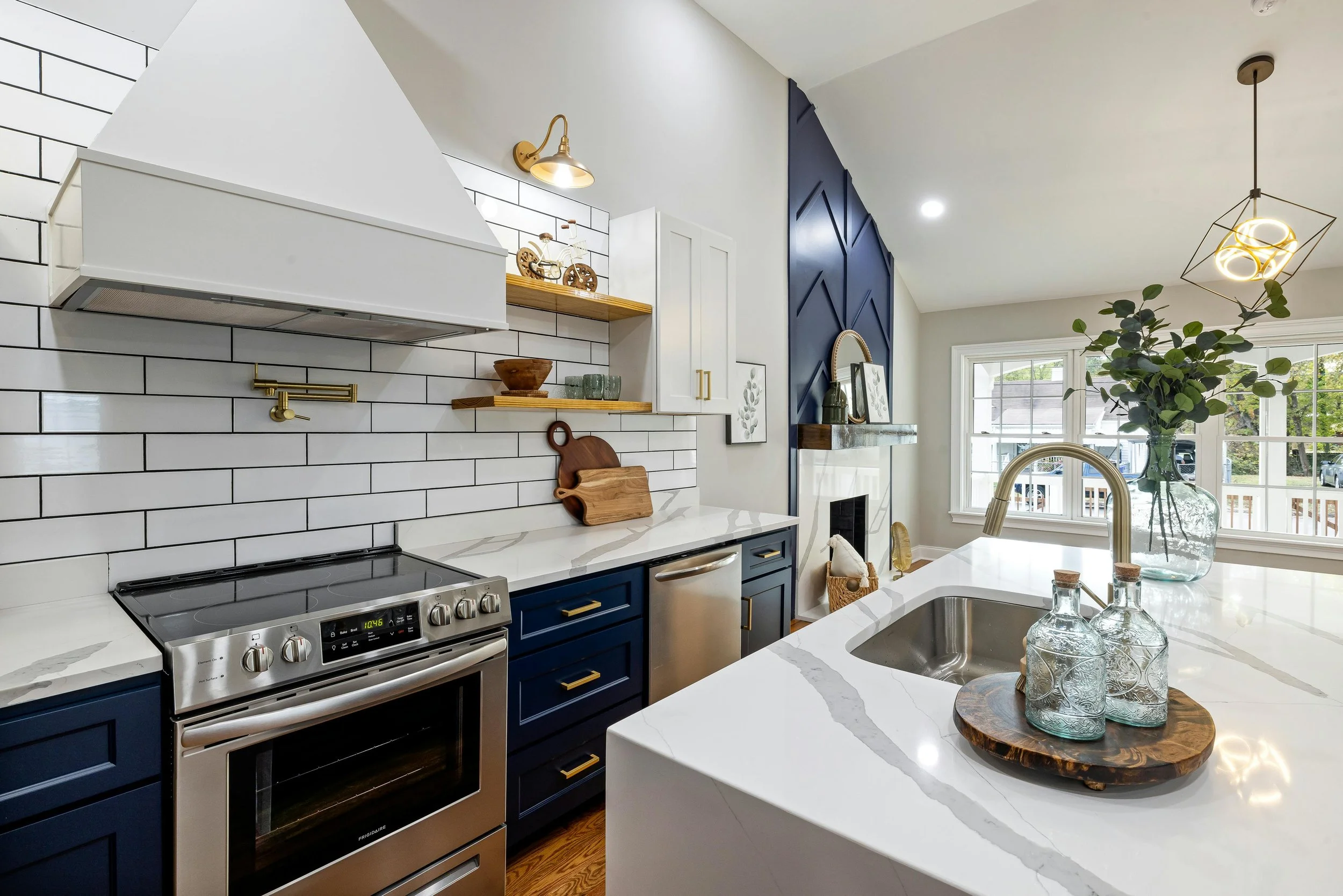 Image of a large kitchen with white tile and countertops and with blue accent cabinets and a blue accent wall