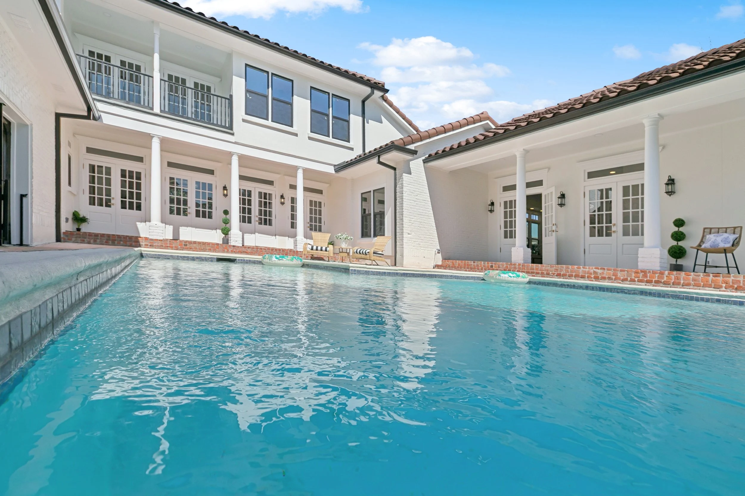 Luxury Listing pictures with Aimee (Amay) Curole, Top Realtor in Metairie, 23 Realty.  Modern backyard with swimming pool surrounded by white house with large windows and columns