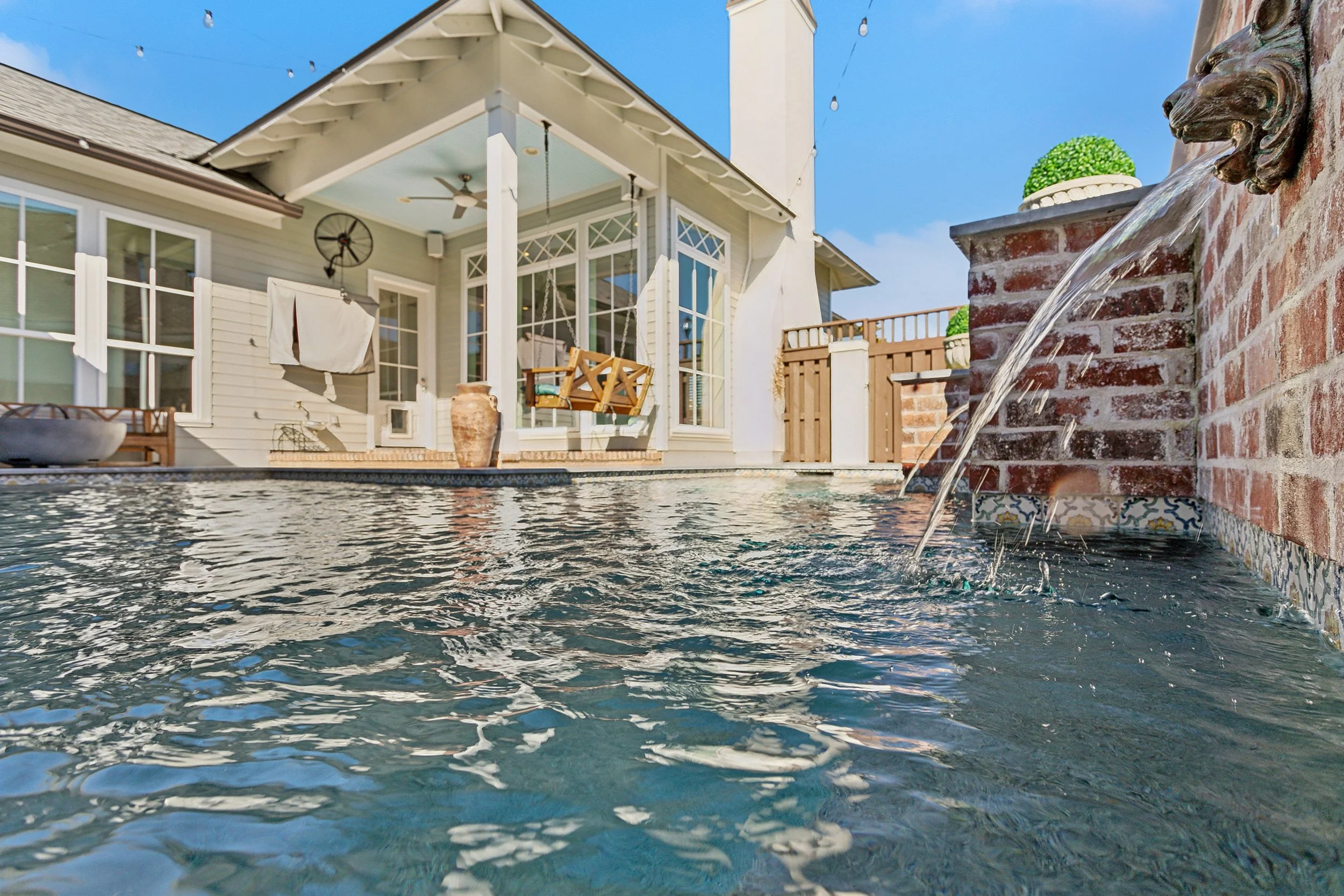 Luxury Listing pictures with Aimee (Amay) Curole, Top Realtor in Metairie, 23 Realty.  Backyard swimming pool near a house with a brick fountain feature.