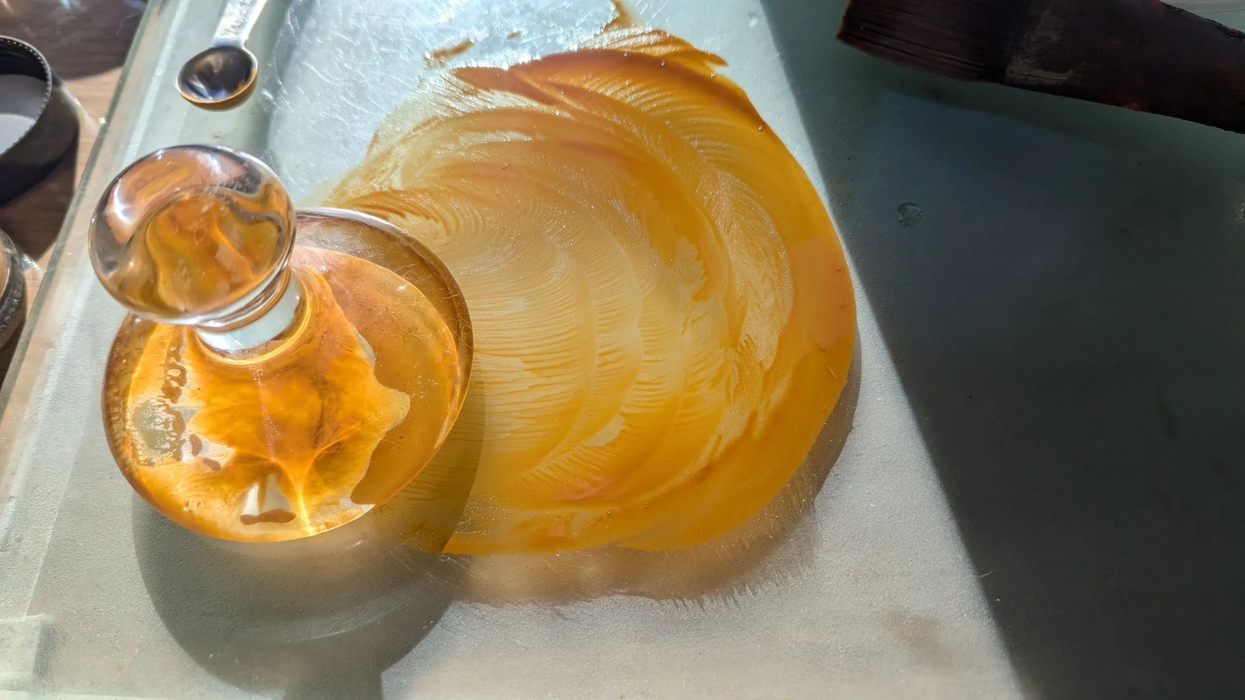 A glass muller and ochre pigment on a glass artist's palette.