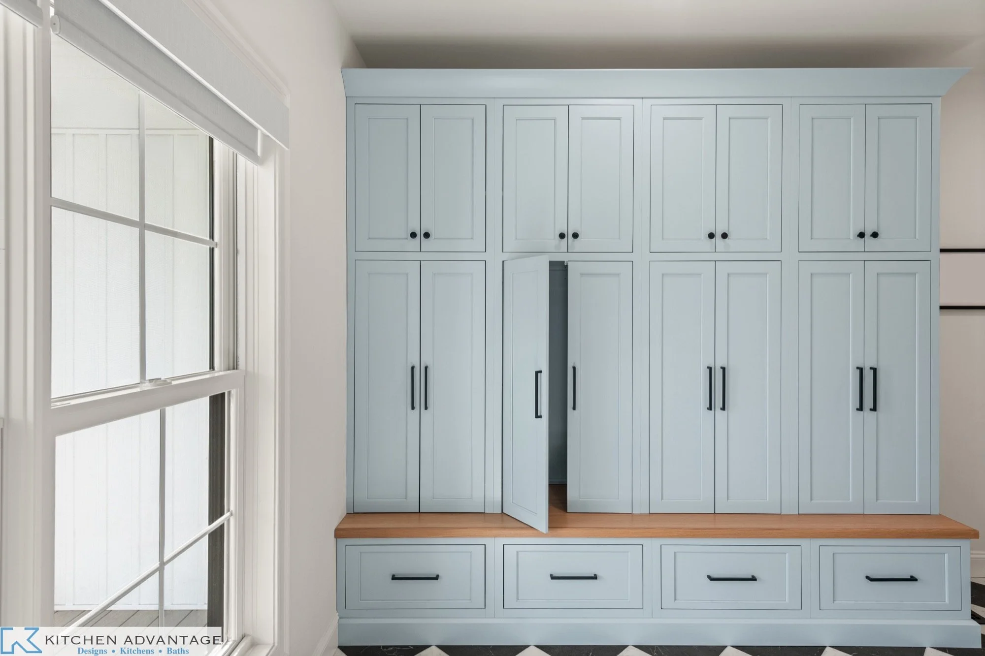 Soft-blue mudroom storage cabinets with a natural wood bench in East Haddam