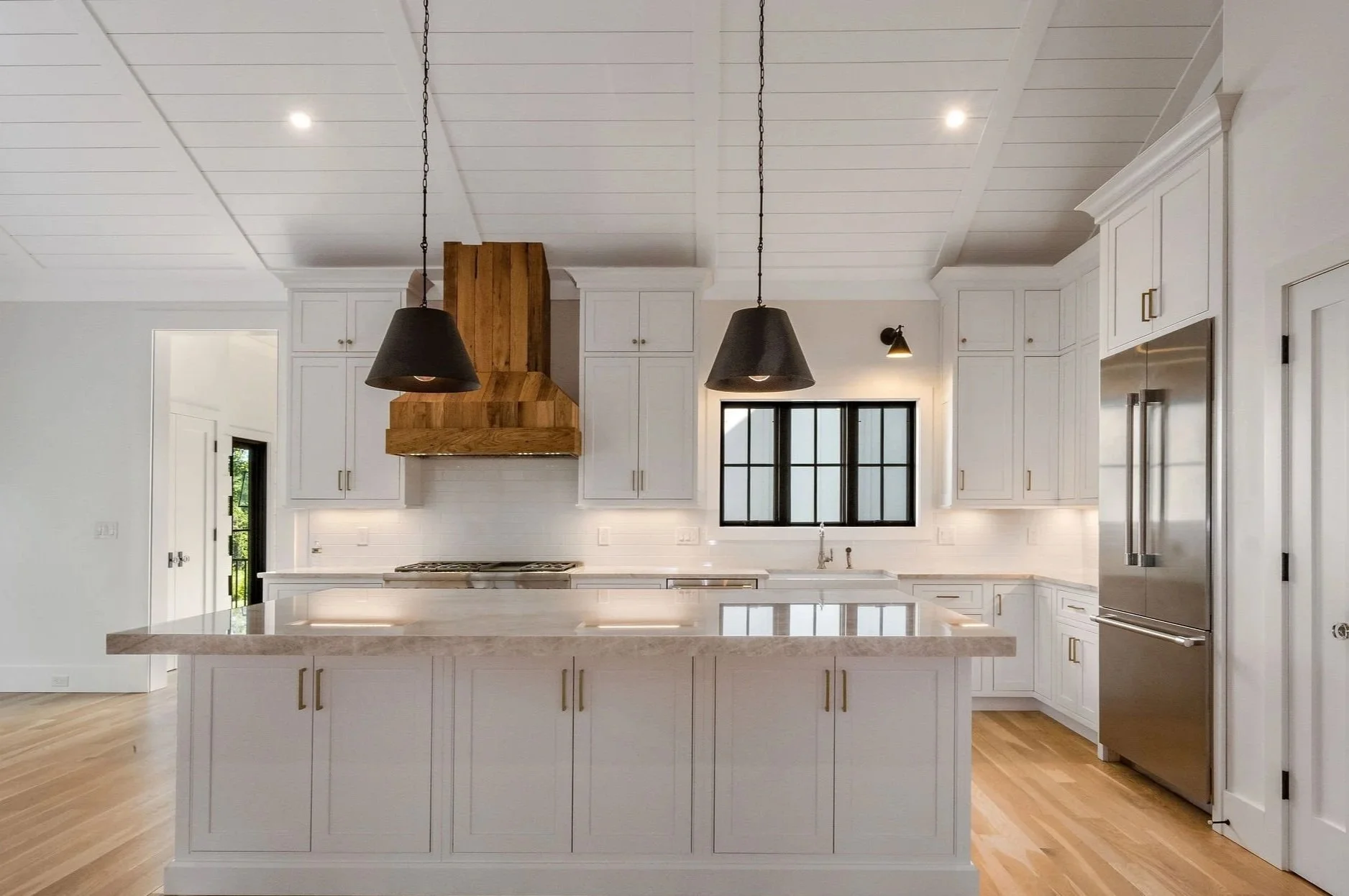 Open-concept Guilford kitchen with white inset cabinetry and a natural-wood range hood