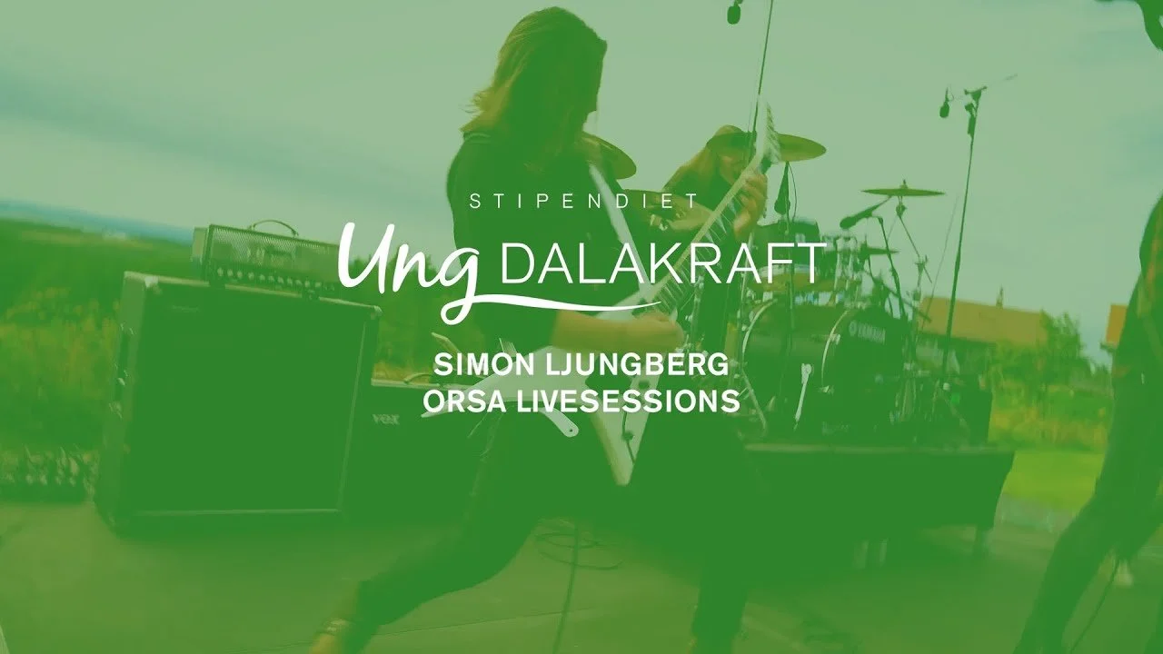 A musician playing an electric guitar outdoors during a live music session, with a drum set and amplifier visible in the background, while the scene is covered in a green filter. The image represents a scholarship for young entrepreneurs.