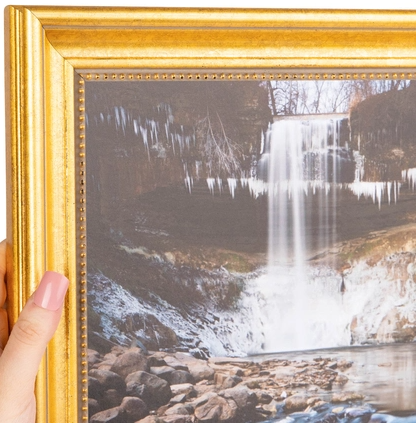 A framed photograph of a waterfall with ice formations in a forested landscape.