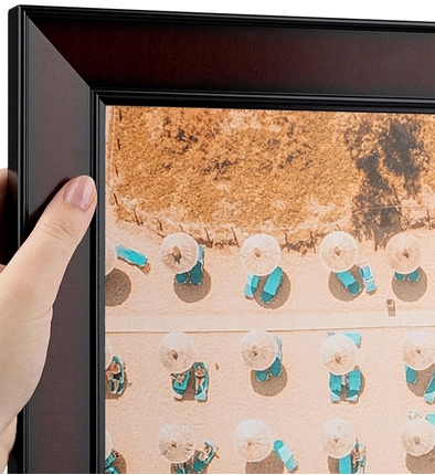 A person holding a framed display of small umbrellas arranged in rows, viewed from above.