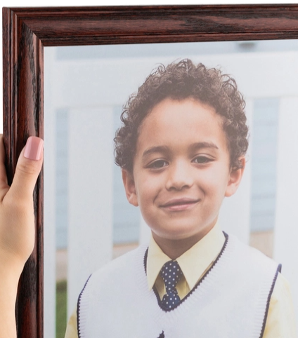 Child's portrait in a wooden picture frame, outdoors background.