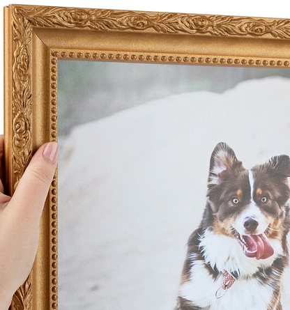 A person holding a framed photograph of a happy dog with a collar, outdoors on a snowy background.