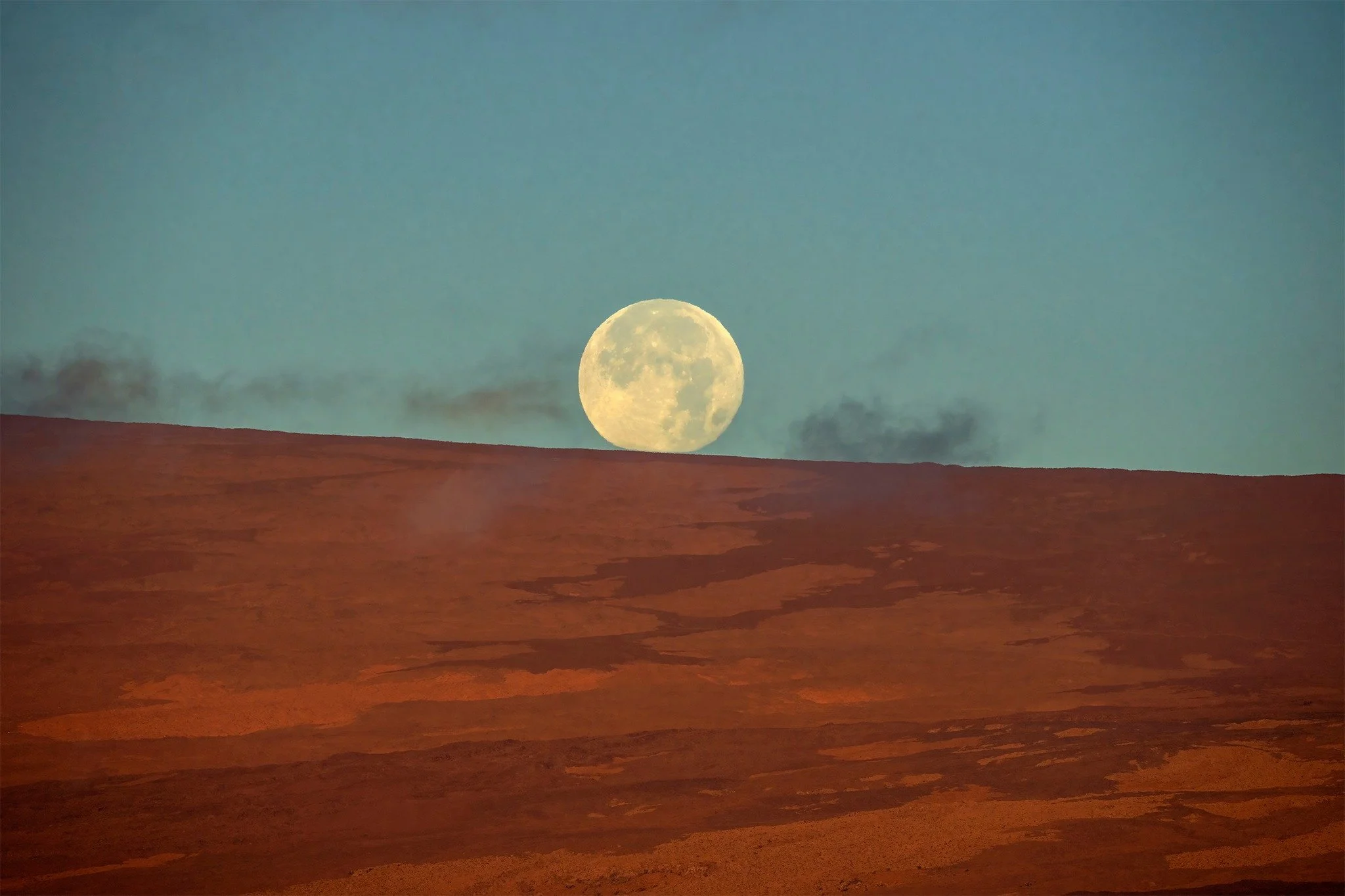 The moon rising over Mauna Loa. 🌕

That rust-red slope is the upper flank of the largest active volcano on Earth &mdash; shot from Kīlauea's summit, where two of the world's most remarkable volcanoes share the same skyline. The moon up there is 2,15