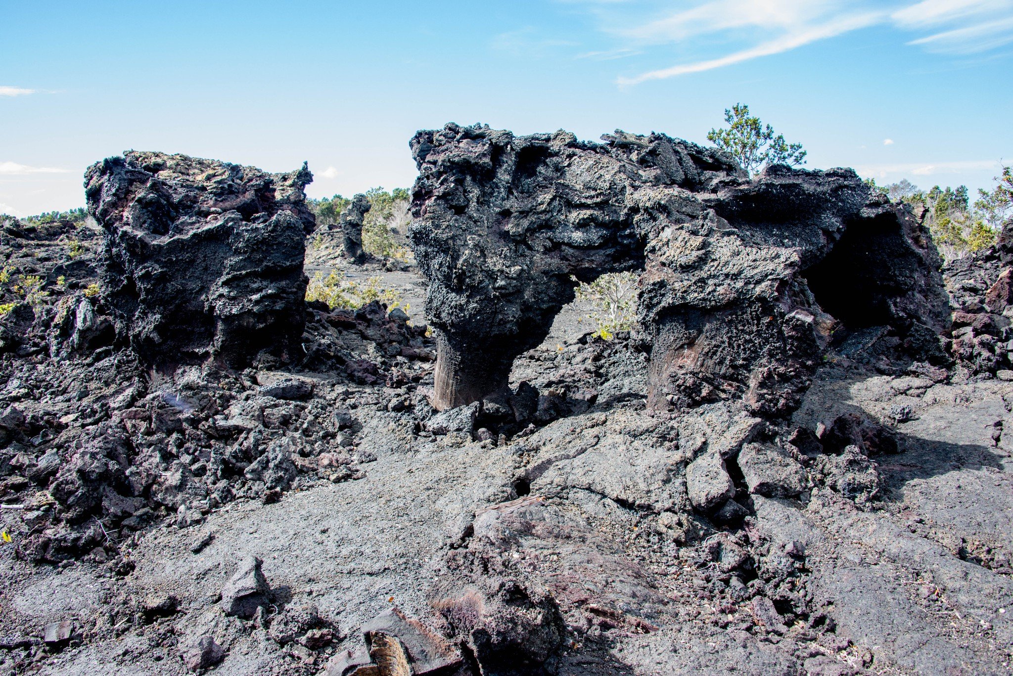 Lava rocks and volcanic terrain under a blue sky with sparse clouds.